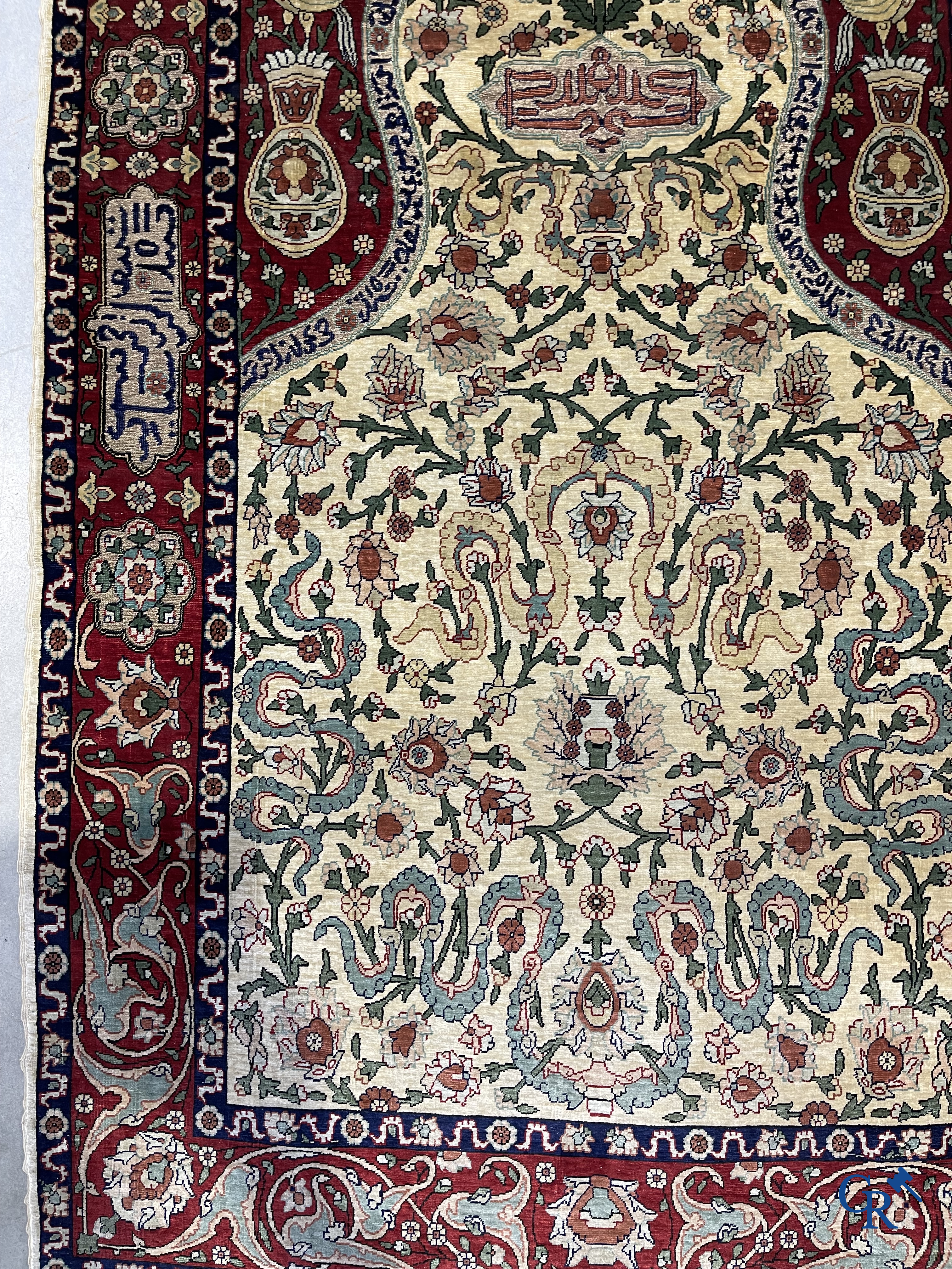 Oosterse tapijten. Een zijden gesigneerd tapijt op donkerrode achtergrond. Inscripties en bewerkt met gouddraad.