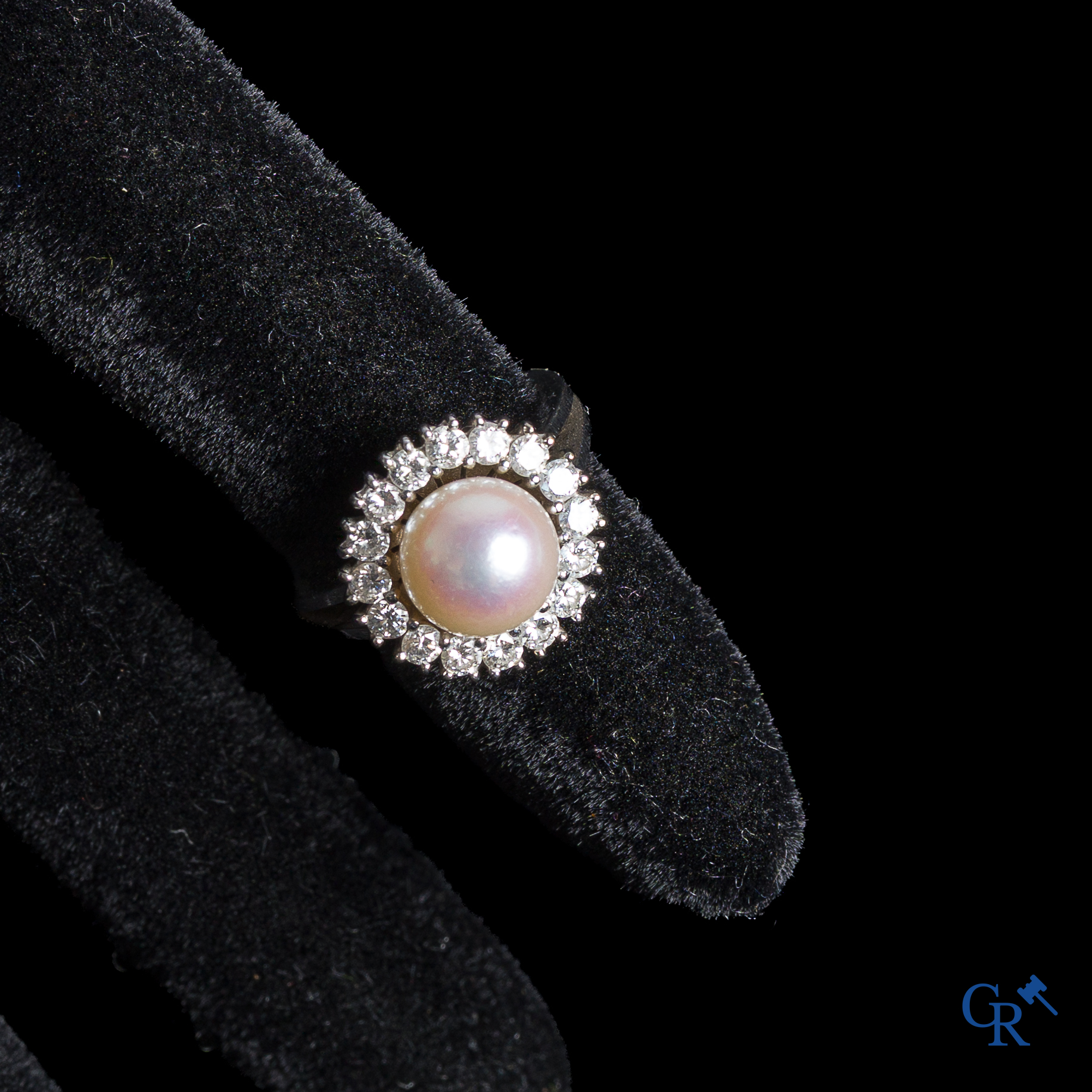 Juwelen. Ring in witgoud 750°/00 bezet met een centrale parel, omringd door briljanten.