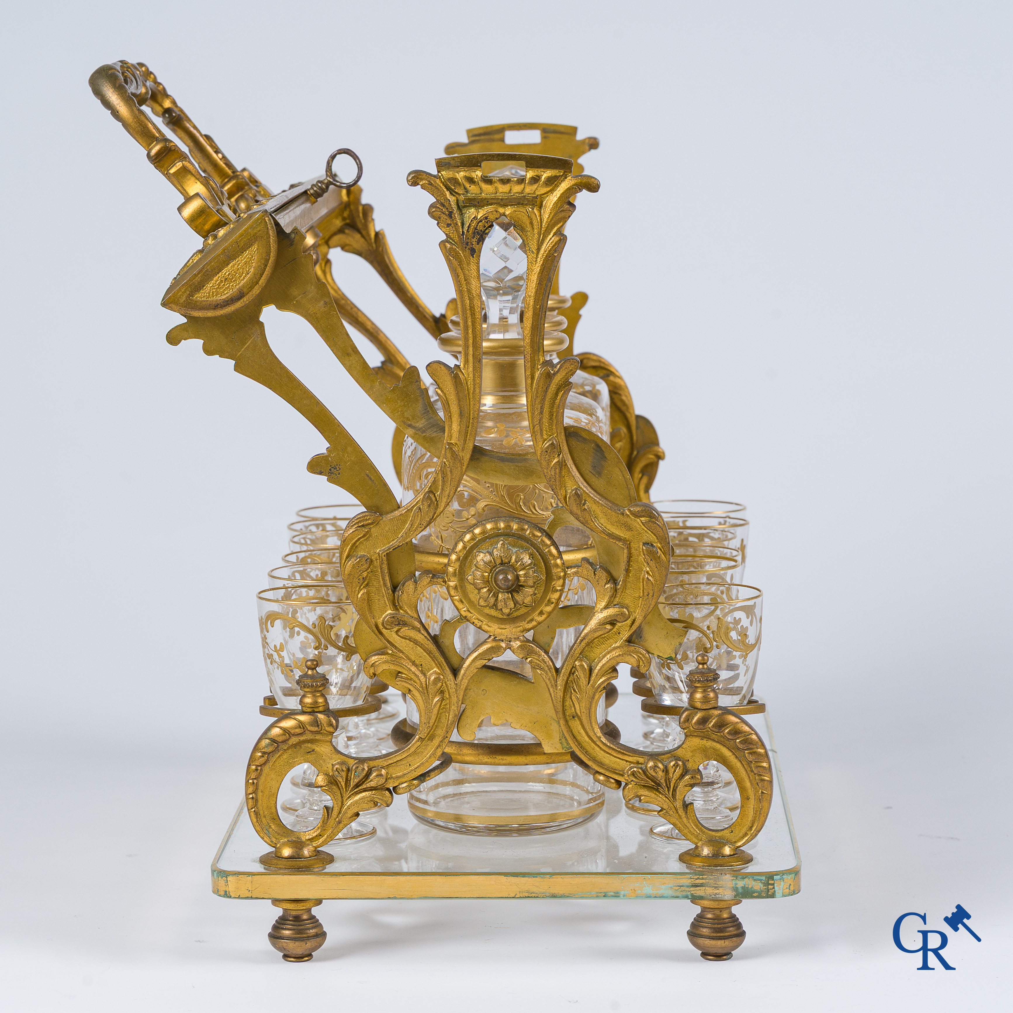 Epoque Napoléon III. Cave à liqueur ouverte en bronze doré avec 3 carafes et 12 verres. Mécanisme de fermeture à clef. Vers 1860.
