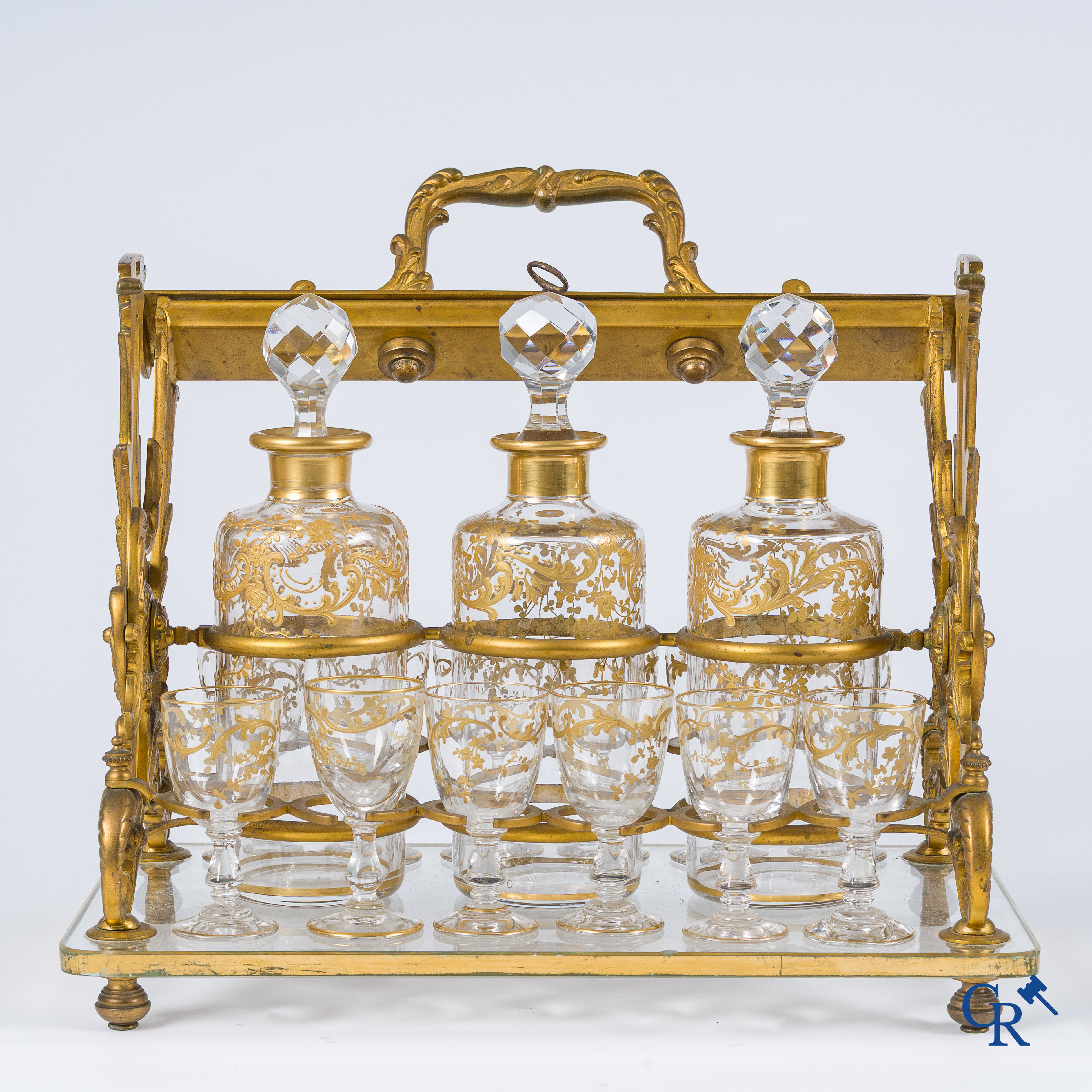 Epoque Napoléon III. Cave à liqueur ouverte en bronze doré avec 3 carafes et 12 verres. Mécanisme de fermeture à clef. Vers 1860.