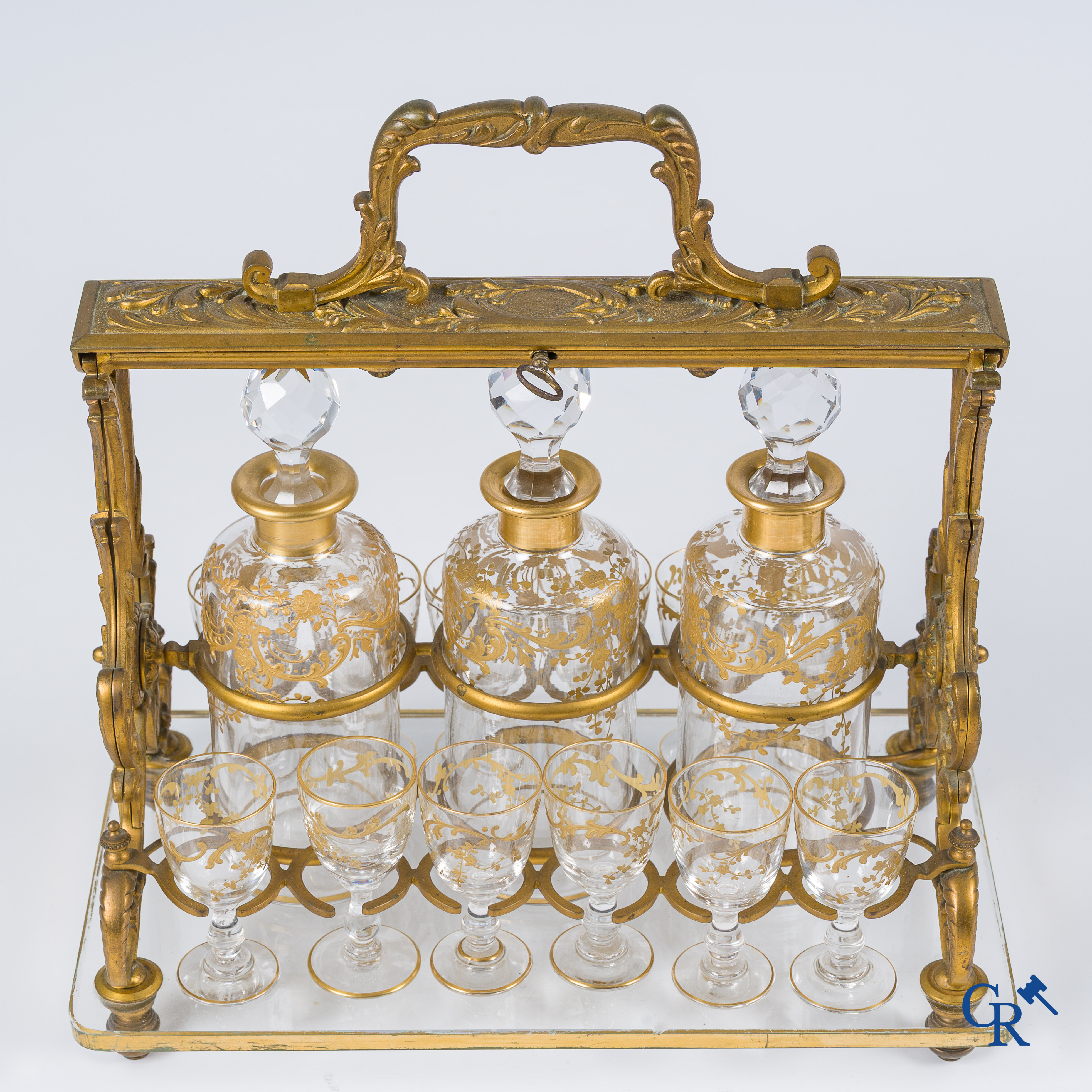 Epoque Napoléon III. Cave à liqueur ouverte en bronze doré avec 3 carafes et 12 verres. Mécanisme de fermeture à clef. Vers 1860.