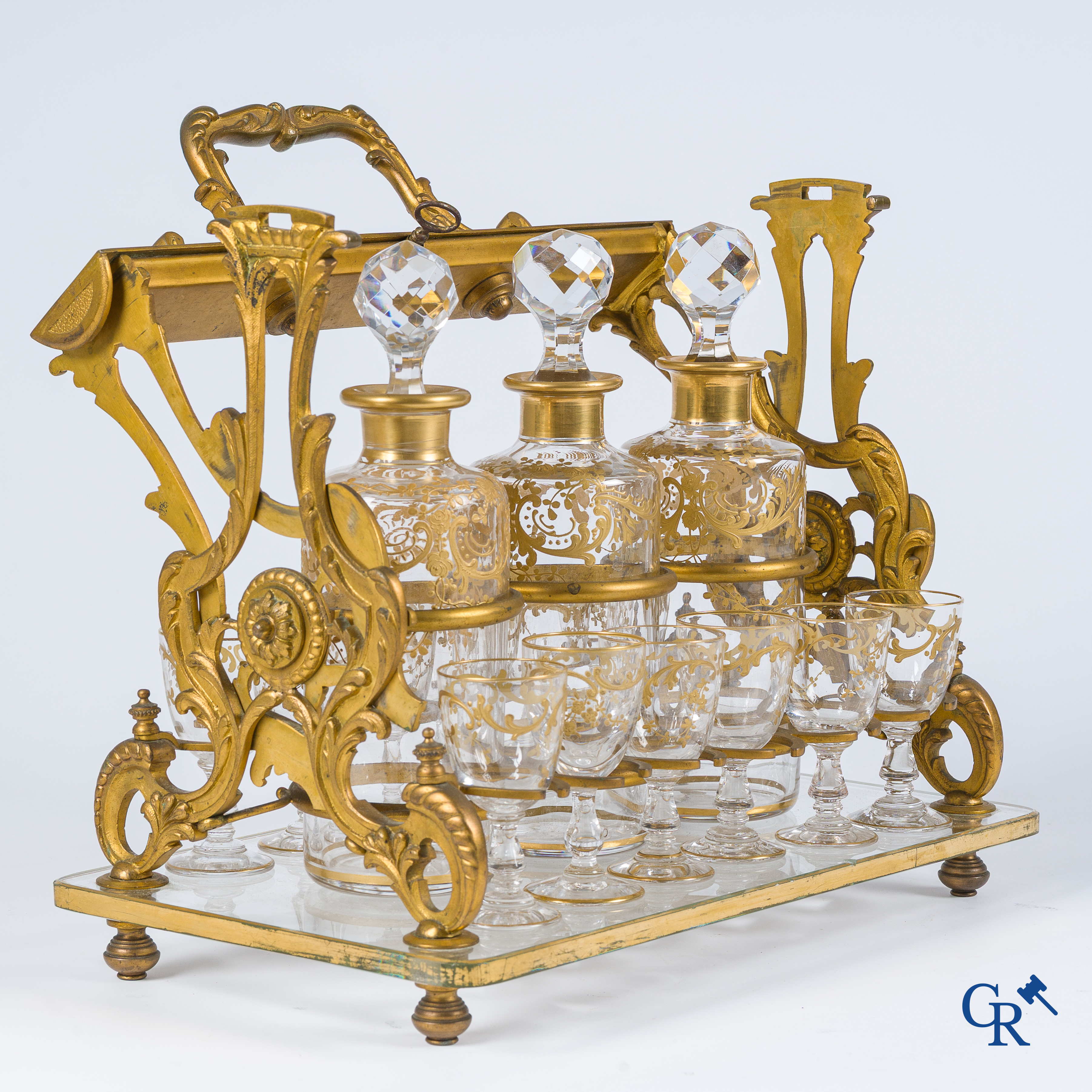 Epoque Napoléon III. Cave à liqueur ouverte en bronze doré avec 3 carafes et 12 verres. Mécanisme de fermeture à clef. Vers 1860.