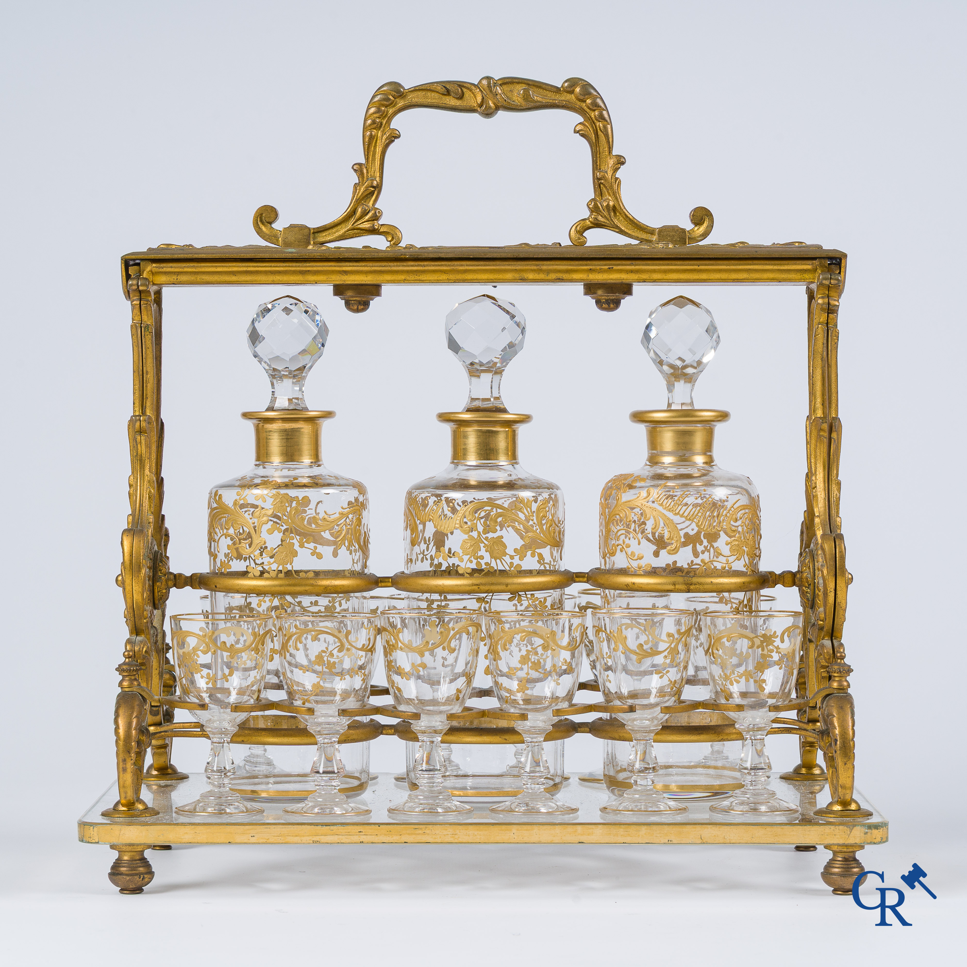 Epoque Napoléon III. Cave à liqueur ouverte en bronze doré avec 3 carafes et 12 verres. Mécanisme de fermeture à clef. Vers 1860.