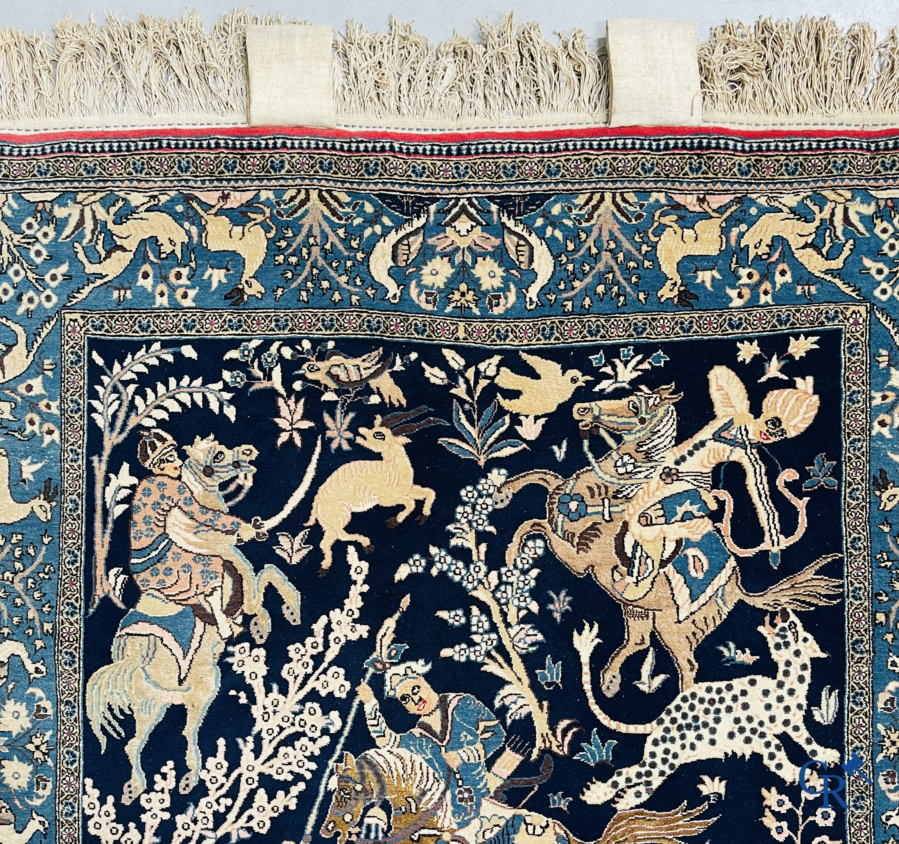 Oosterse tapijten. Ghoum, een fijn geknoopt Perzisch tapijt met ruiters te paard op een donkerblauwe achtergrond.