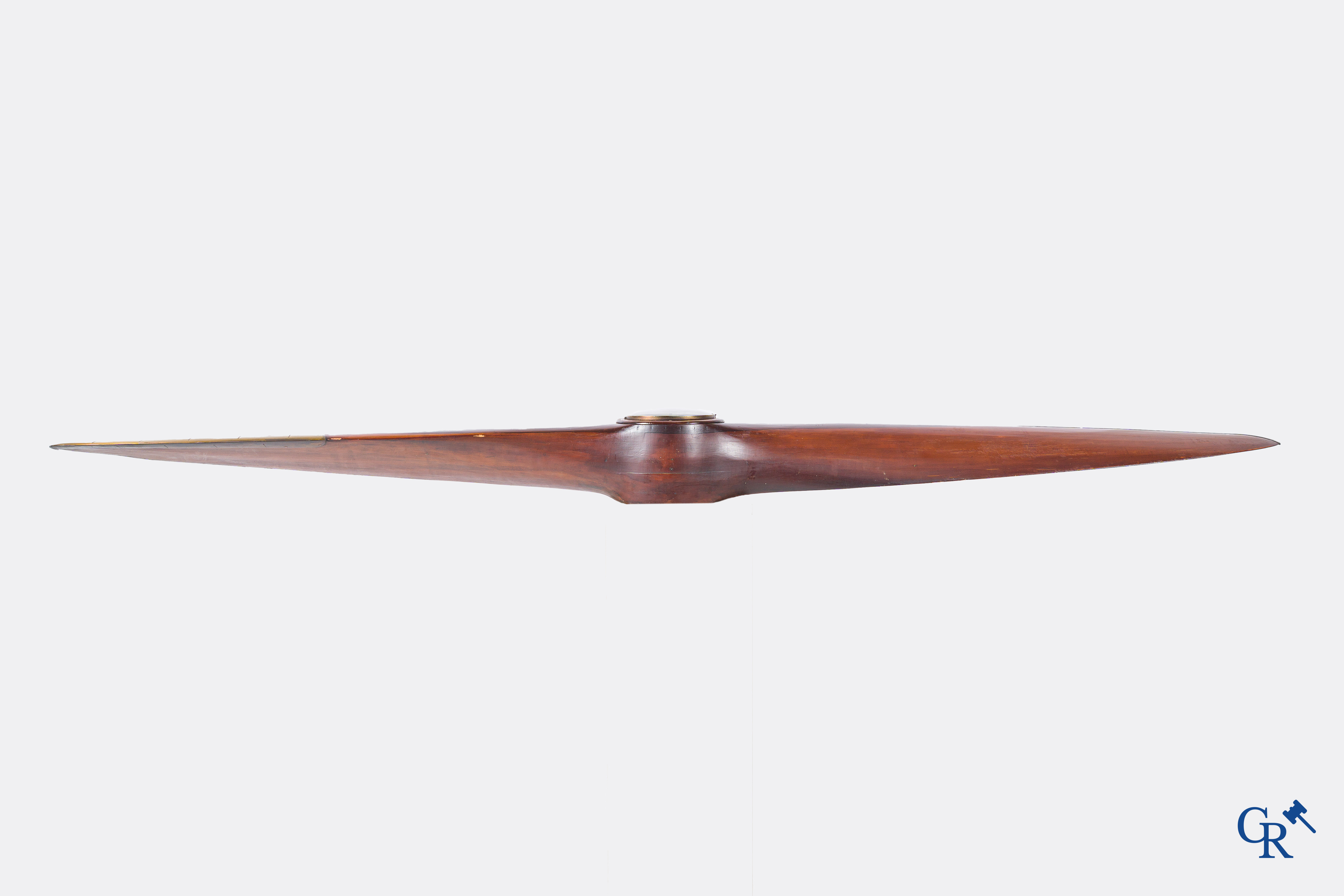 Een grote houten propeller of luchtschroef met koperbeslag en later ingewerkt uurwerk.