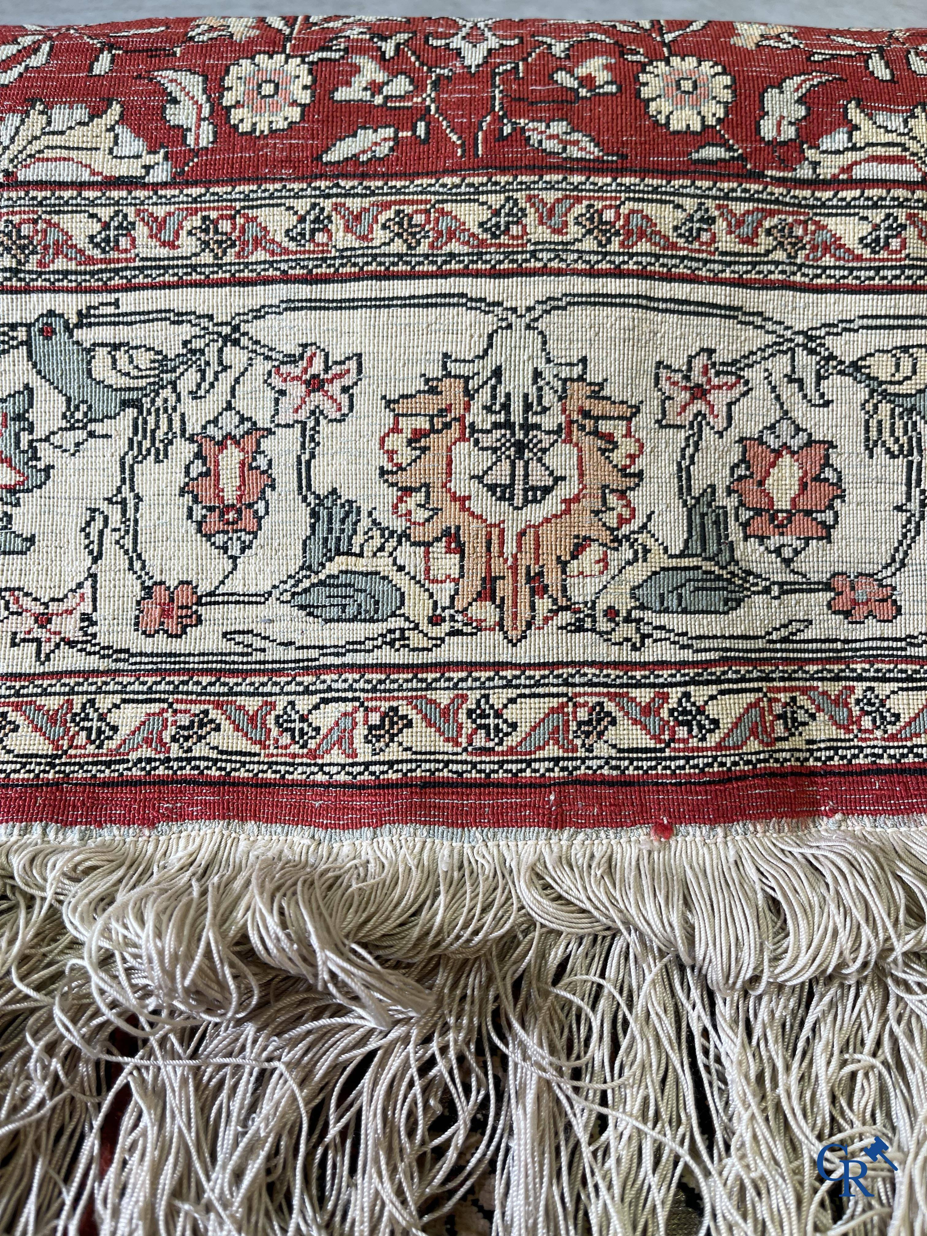 Oriental carpets, a hand-knotted carpet in silk with forest animals in a floral decor on a background in gold thread.