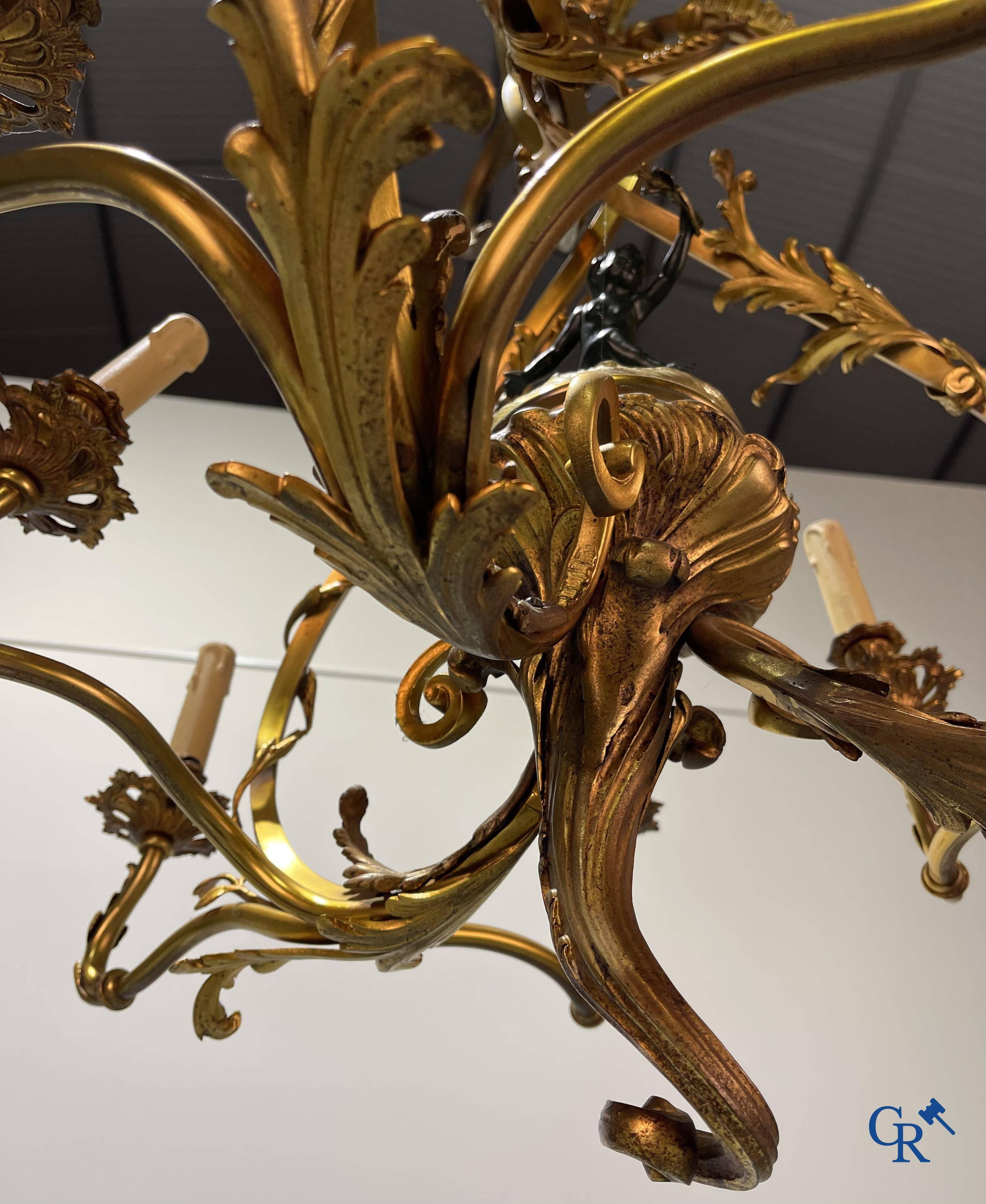 A bronze chandelier with putti and 9 light points in LXV style. Circa 1920.