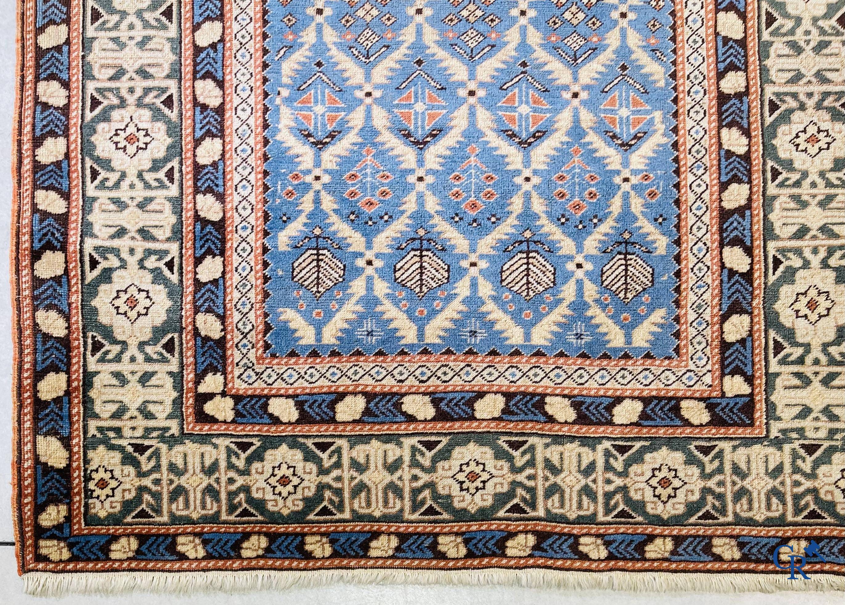 Antieke Oosterse tapijten, een antiek Dagestan tapijt met motieven op een blauwe achtergrond.