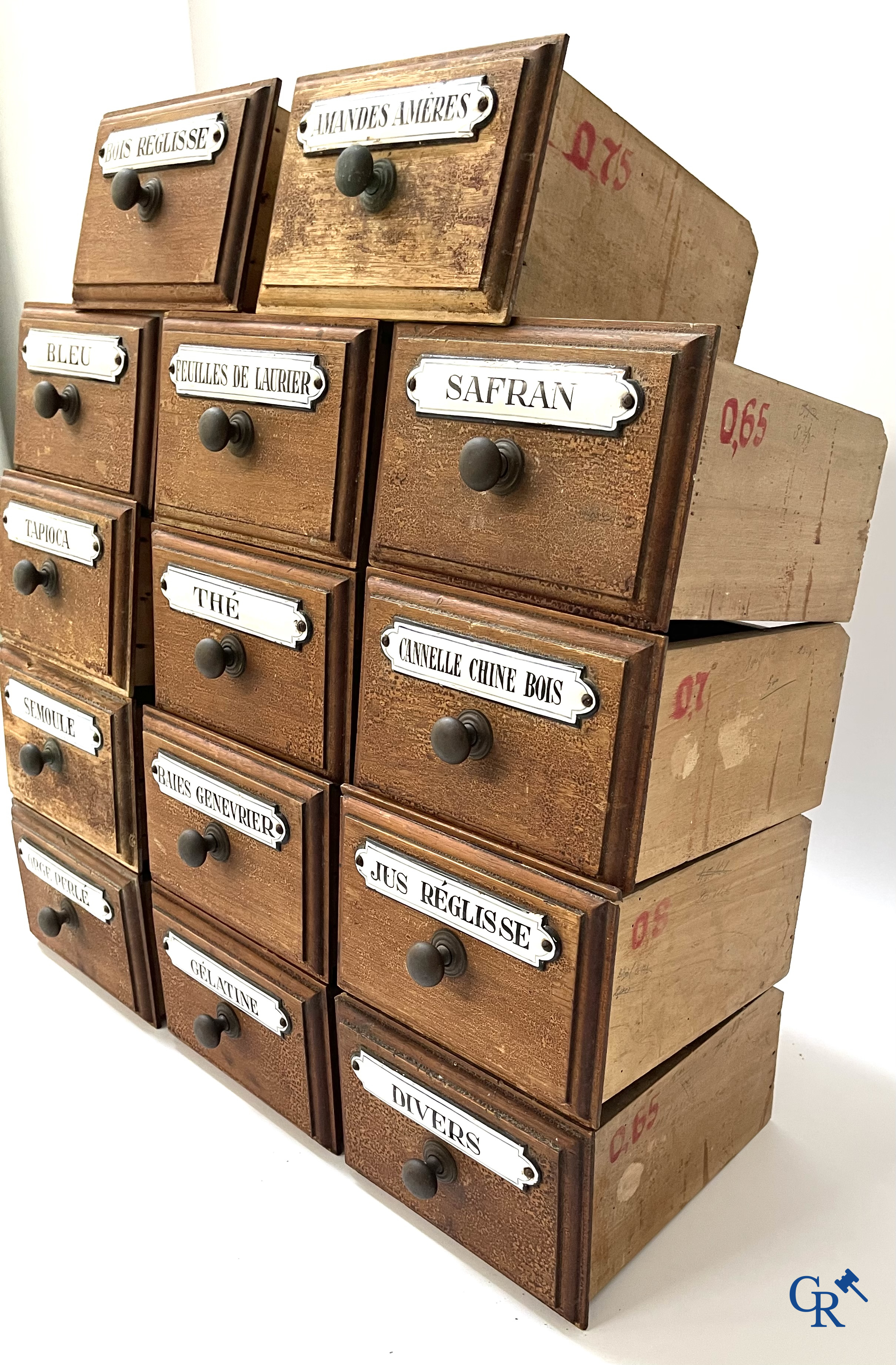 14 laden met emaille bordjes voor kruiden, specerijen en andere afkomstig van een winkelmeubel. Circa 1920.