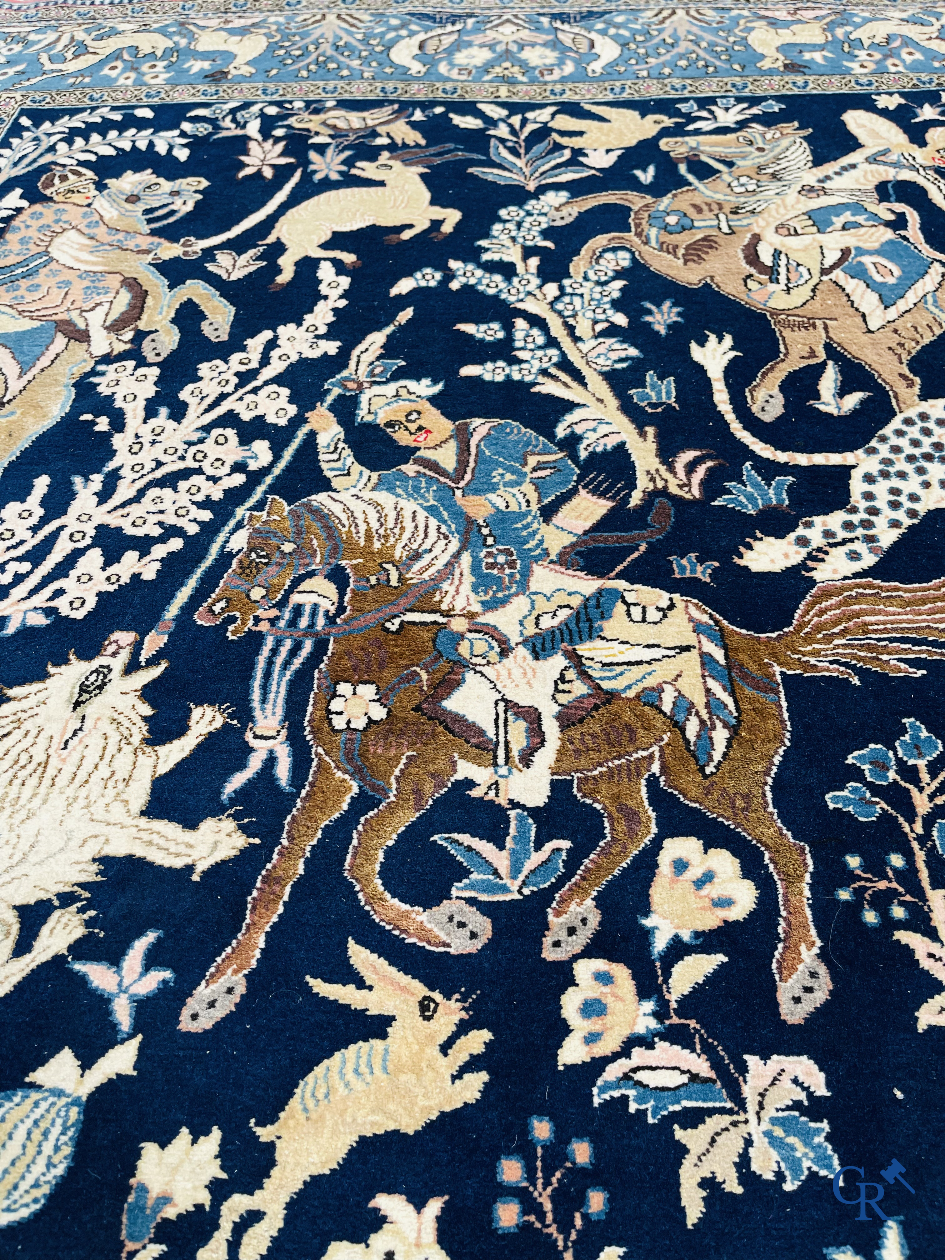 Oosterse tapijten. Ghoum, een fijn geknoopt Perzisch tapijt met ruiters te paard op een donkerblauwe achtergrond.