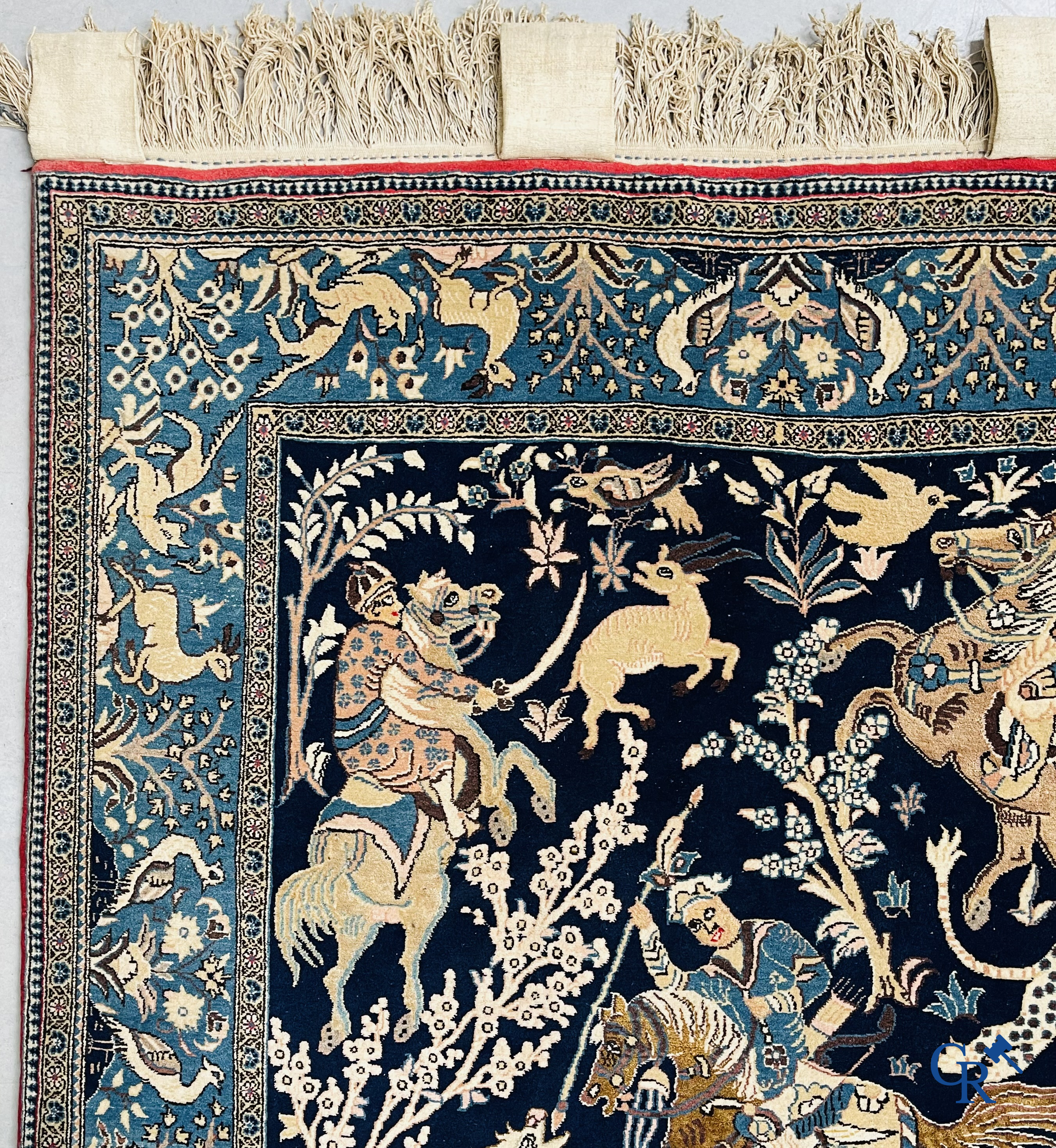 Oosterse tapijten. Ghoum, een fijn geknoopt Perzisch tapijt met ruiters te paard op een donkerblauwe achtergrond.