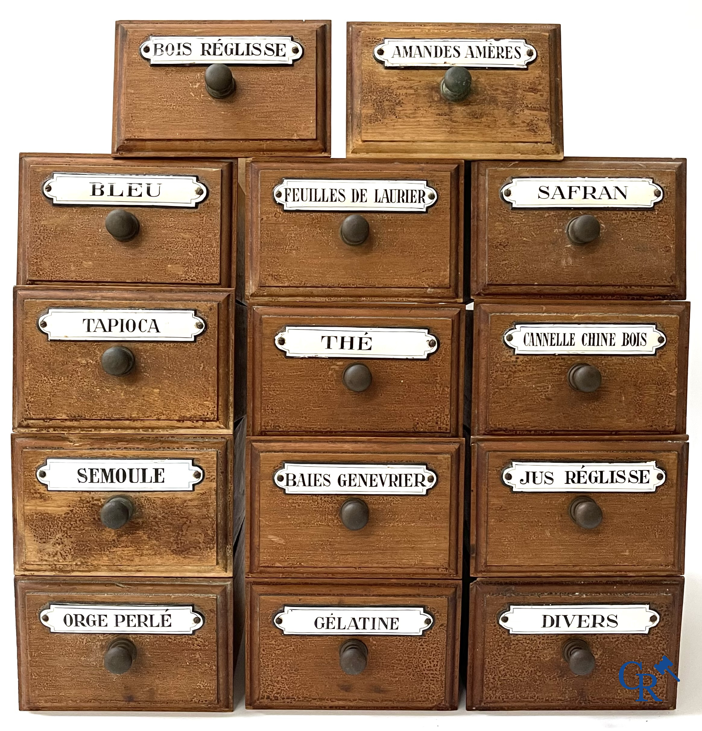 14 laden met emaille bordjes voor kruiden, specerijen en andere afkomstig van een winkelmeubel. Circa 1920.