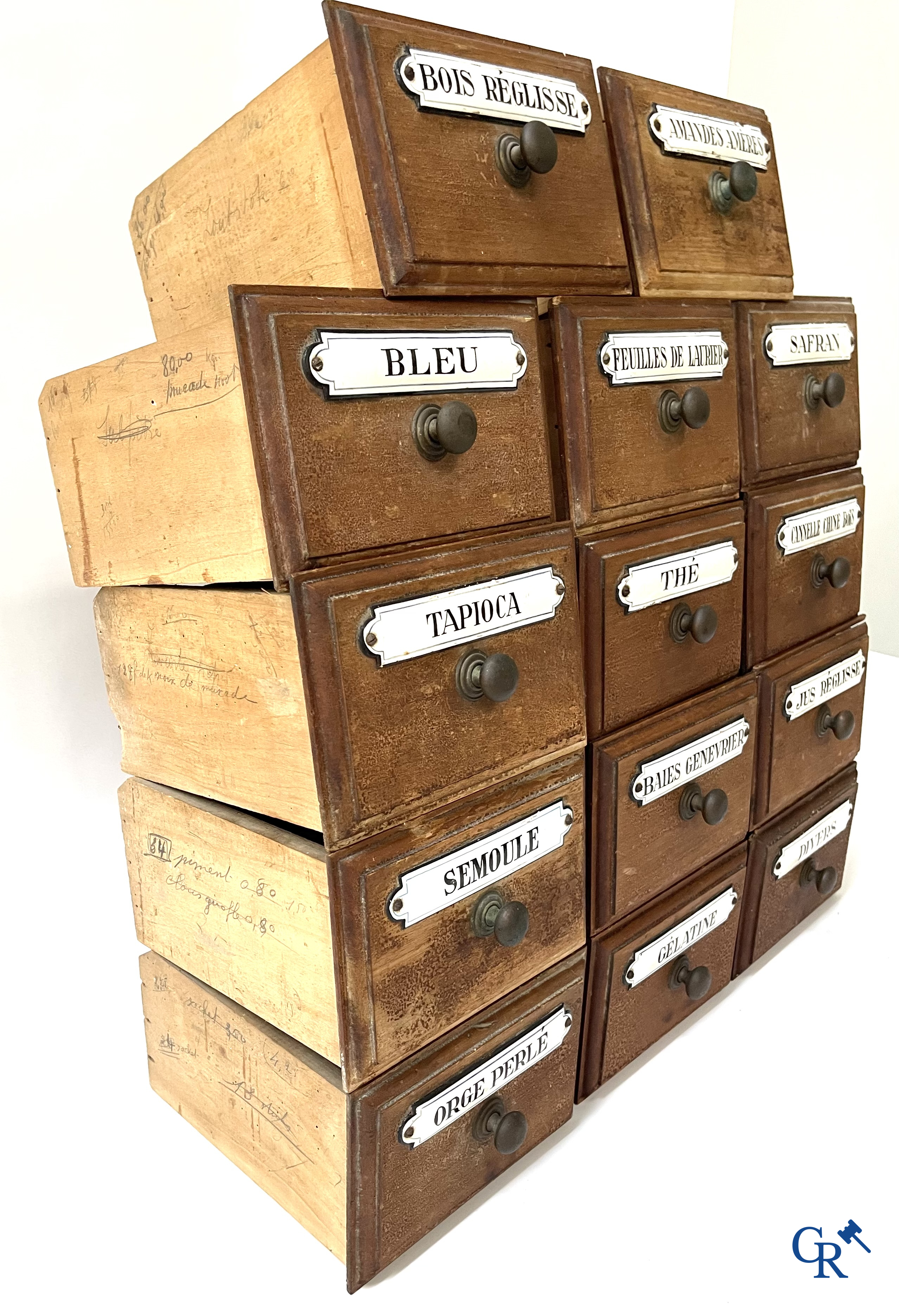 14 laden met emaille bordjes voor kruiden, specerijen en andere afkomstig van een winkelmeubel. Circa 1920.