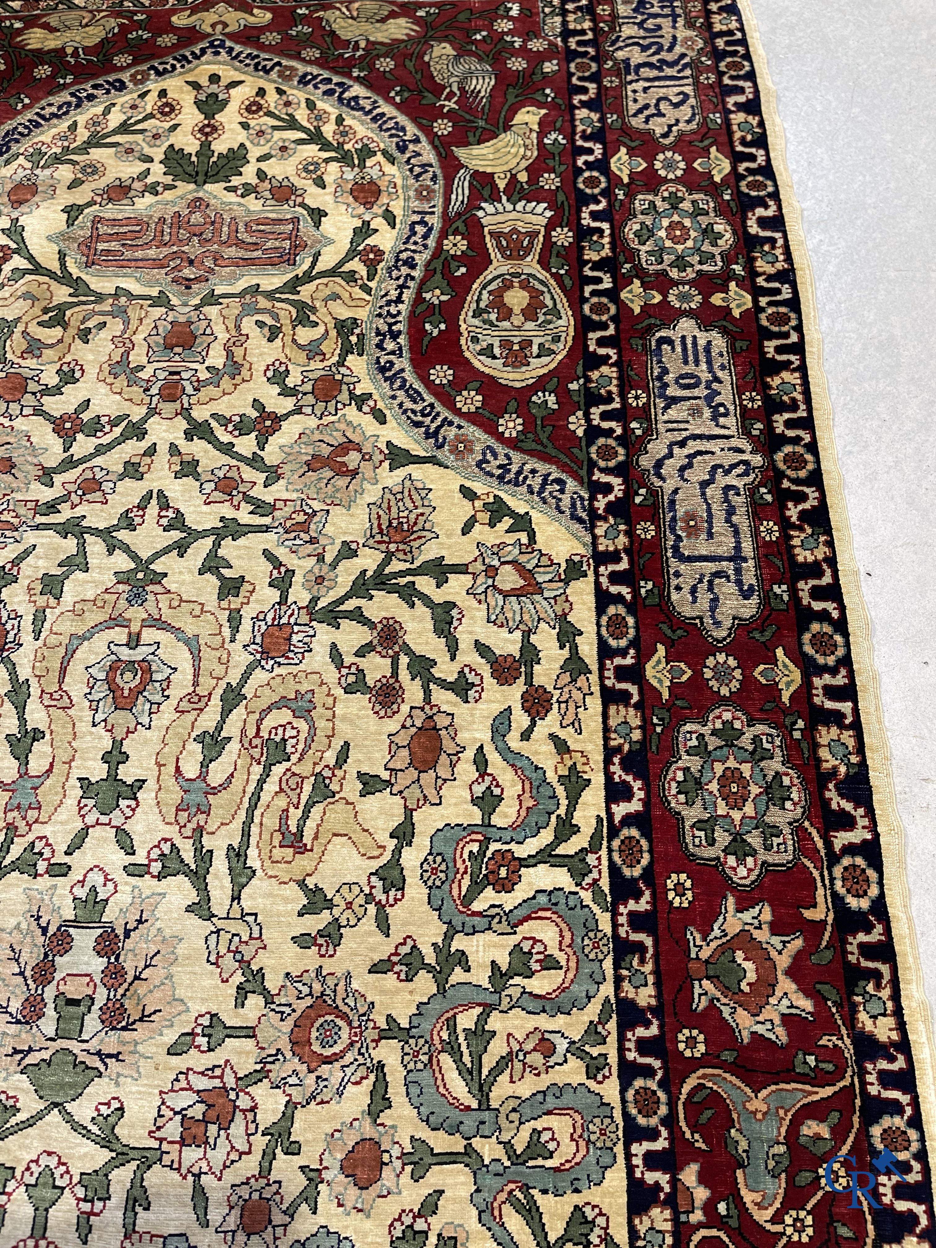 Oosterse tapijten. Een zijden gesigneerd tapijt op donkerrode achtergrond. Inscripties en bewerkt met gouddraad.