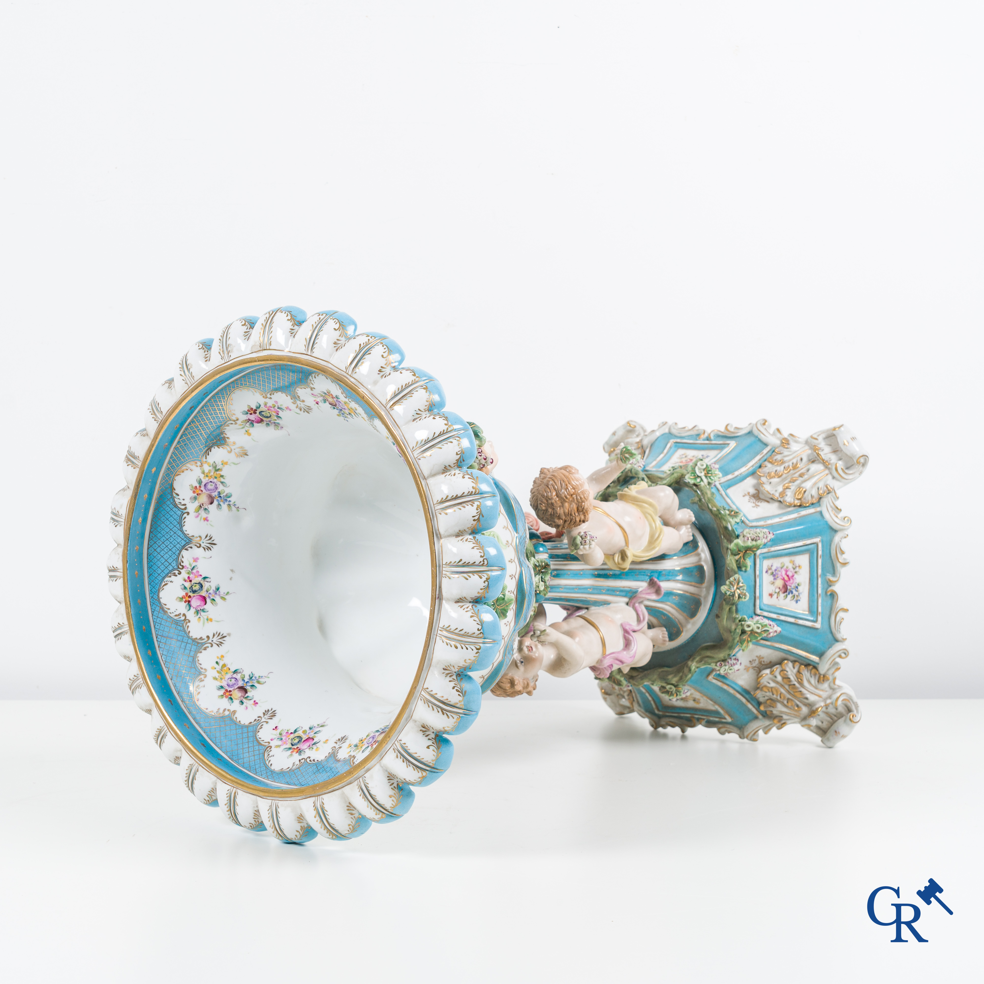 Een grote pronkcoupe in porselein met putti, druivenranken en bacchus hoofden. 20ste eeuw.