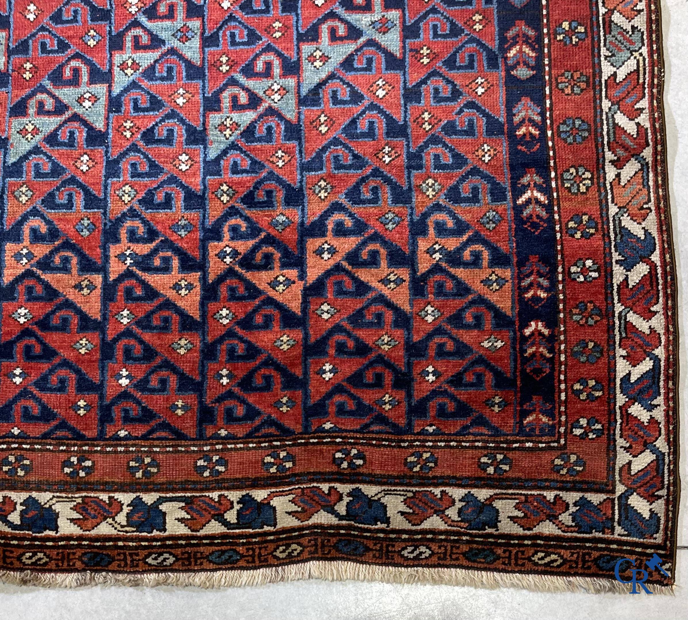 Oosterse tapijten, een antiek oosters tapijt met motieven op een donkerrode achtergrond.