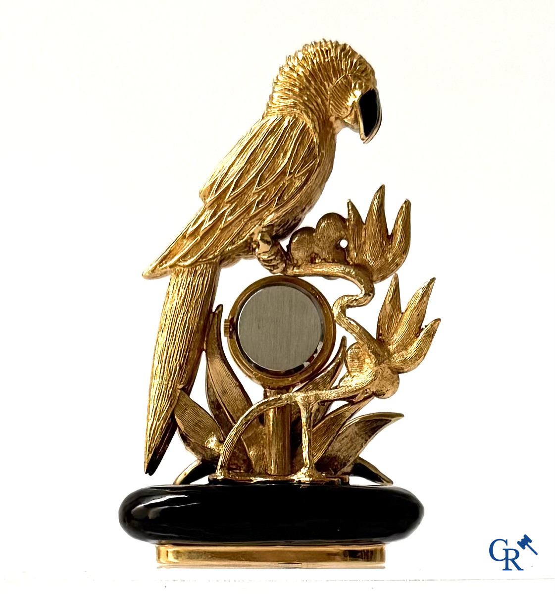 Uurwerken. Een klein klokje met voorstelling van een papegaai. Emaille op verguld metaal ingelegd met gesteente.