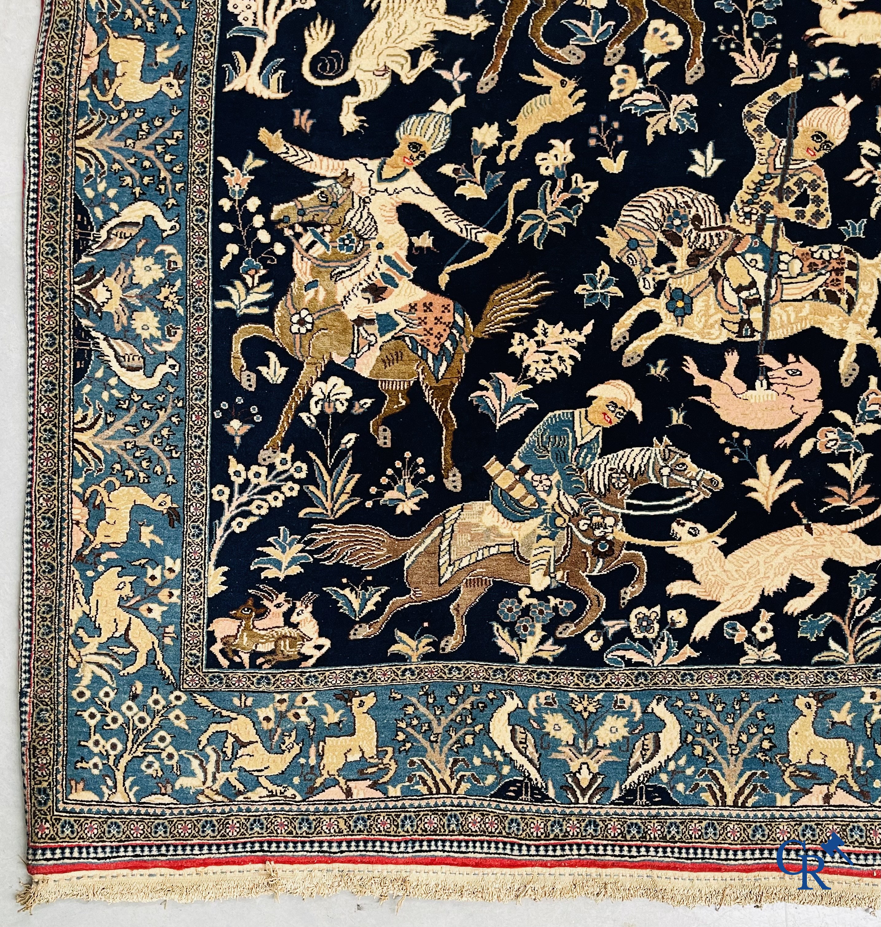 Oosterse tapijten. Ghoum, een fijn geknoopt Perzisch tapijt met ruiters te paard op een donkerblauwe achtergrond.