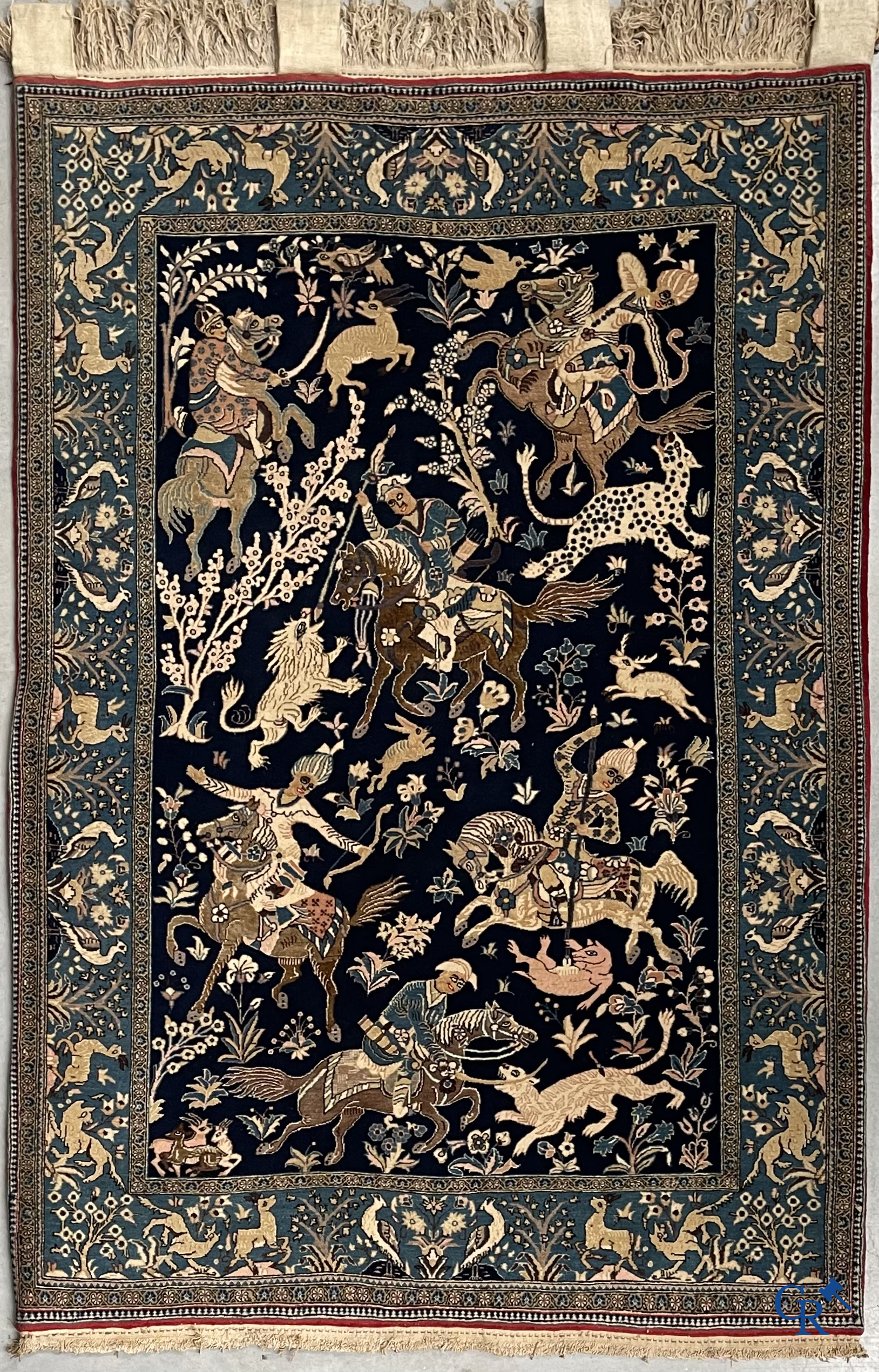 Oosterse tapijten. Ghoum, een fijn geknoopt Perzisch tapijt met ruiters te paard op een donkerblauwe achtergrond.