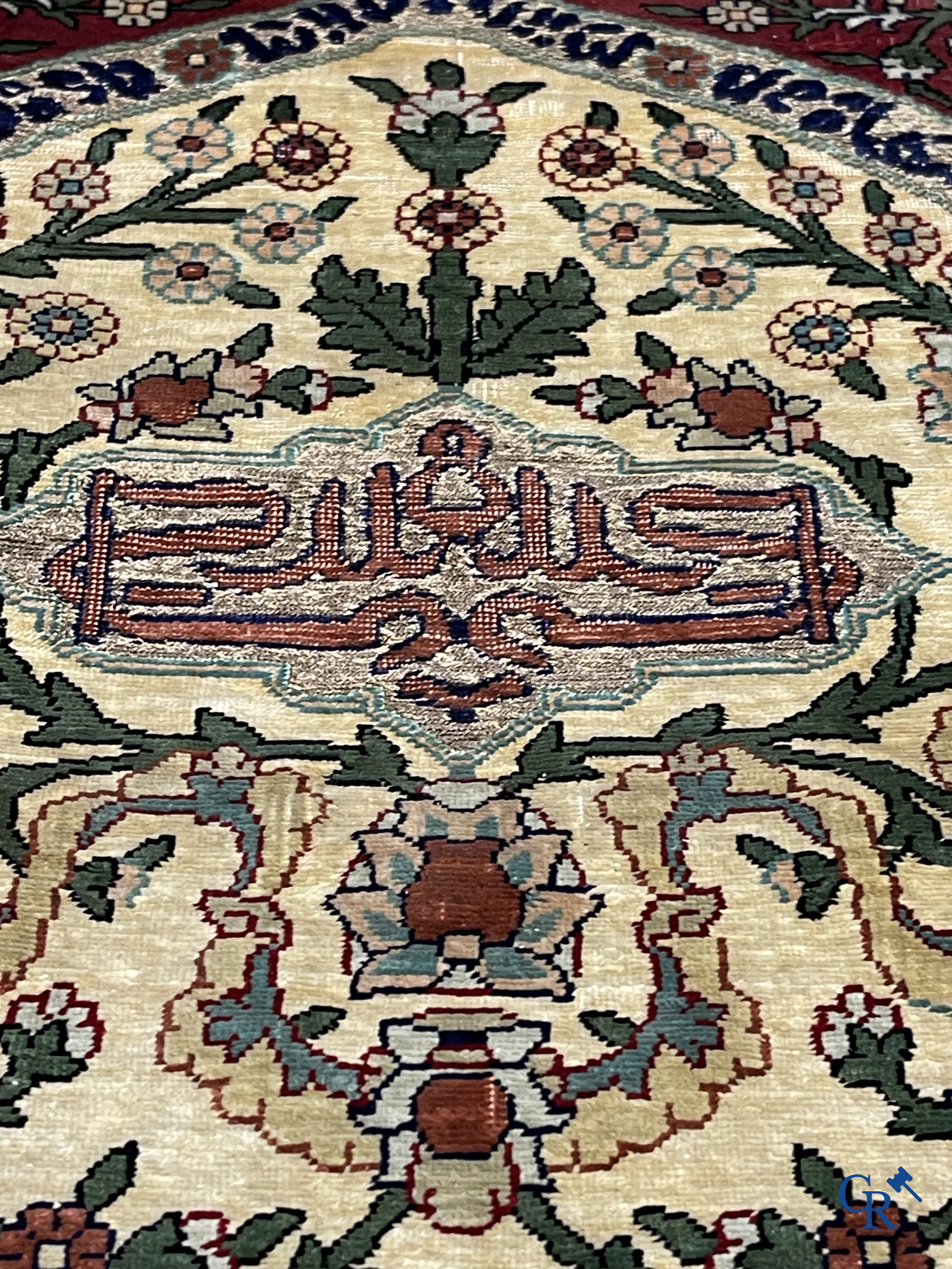 Oosterse tapijten. Een zijden gesigneerd tapijt op donkerrode achtergrond. Inscripties en bewerkt met gouddraad.