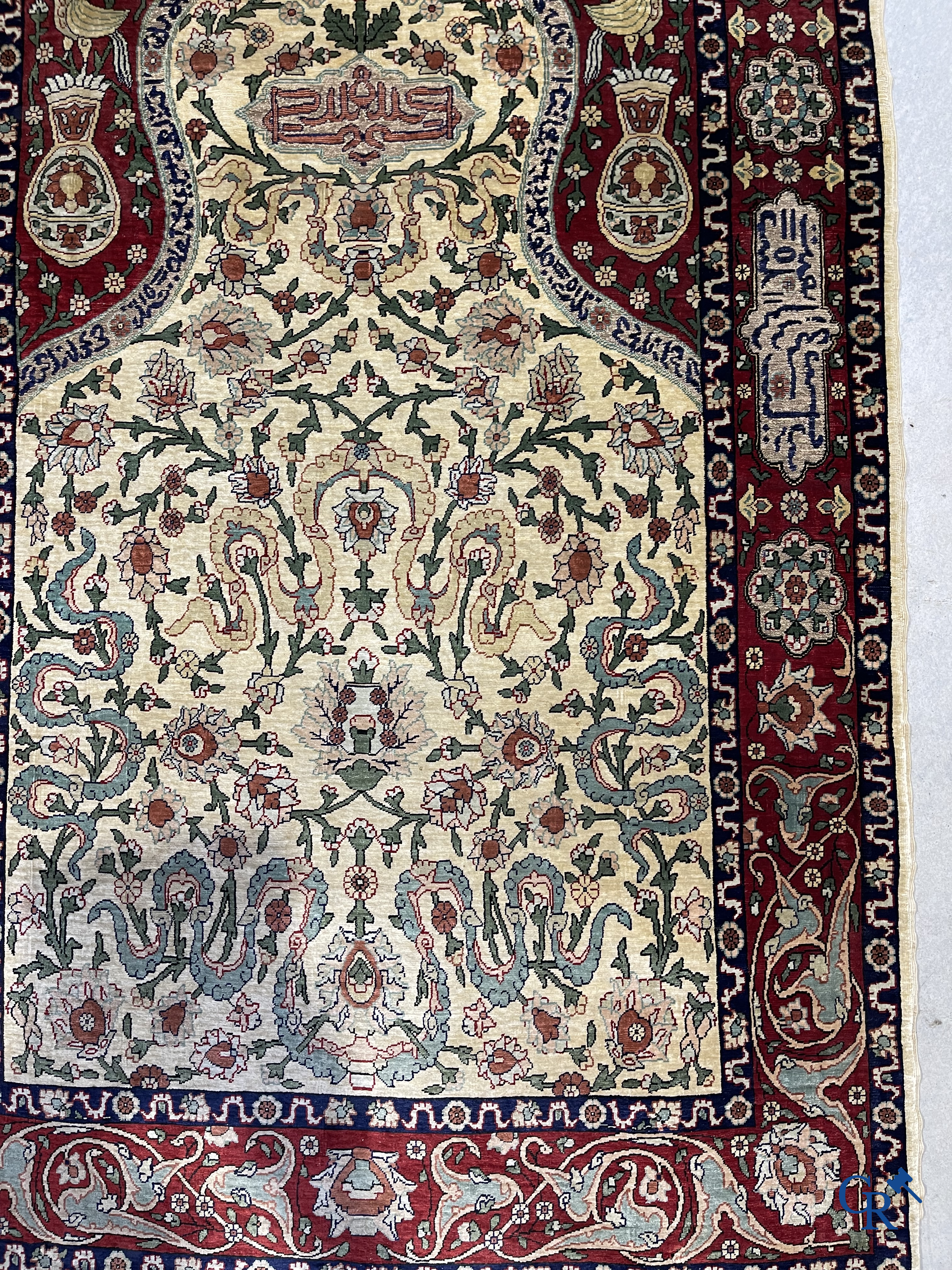 Oosterse tapijten. Een zijden gesigneerd tapijt op donkerrode achtergrond. Inscripties en bewerkt met gouddraad.