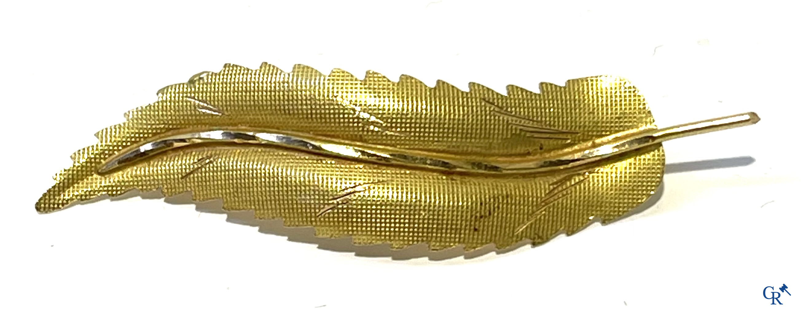 Juwelen, een bladvormige broche in goud 750°/00 en een bedelarmband in verschillende gehaltes goud.