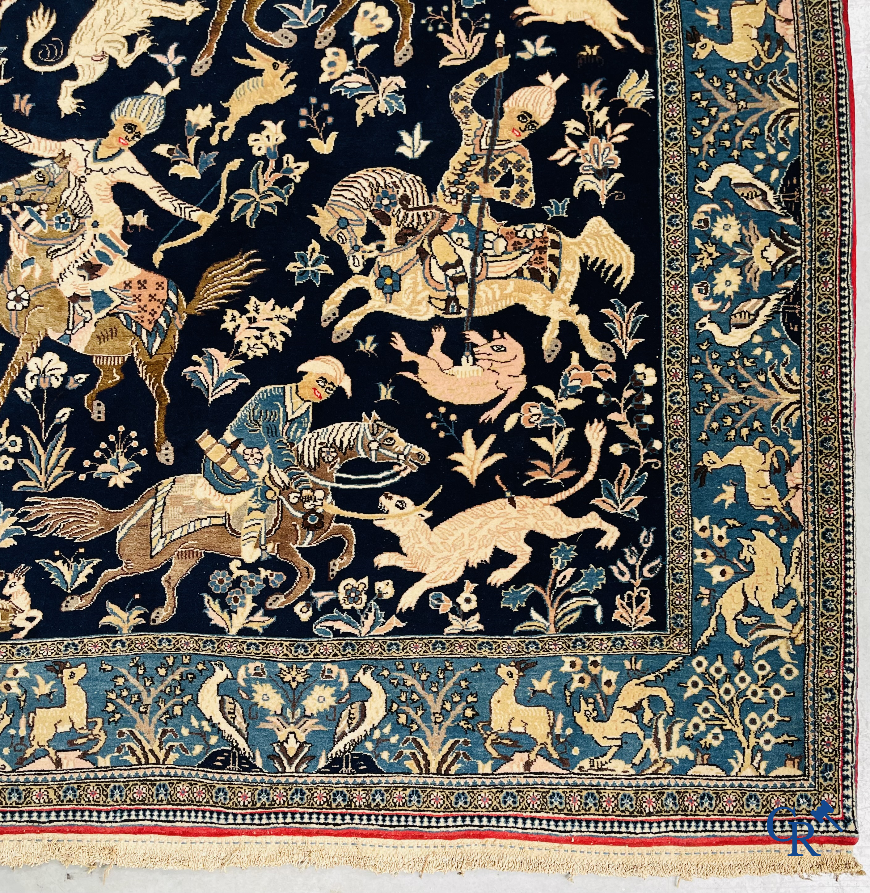 Oosterse tapijten. Ghoum, een fijn geknoopt Perzisch tapijt met ruiters te paard op een donkerblauwe achtergrond.