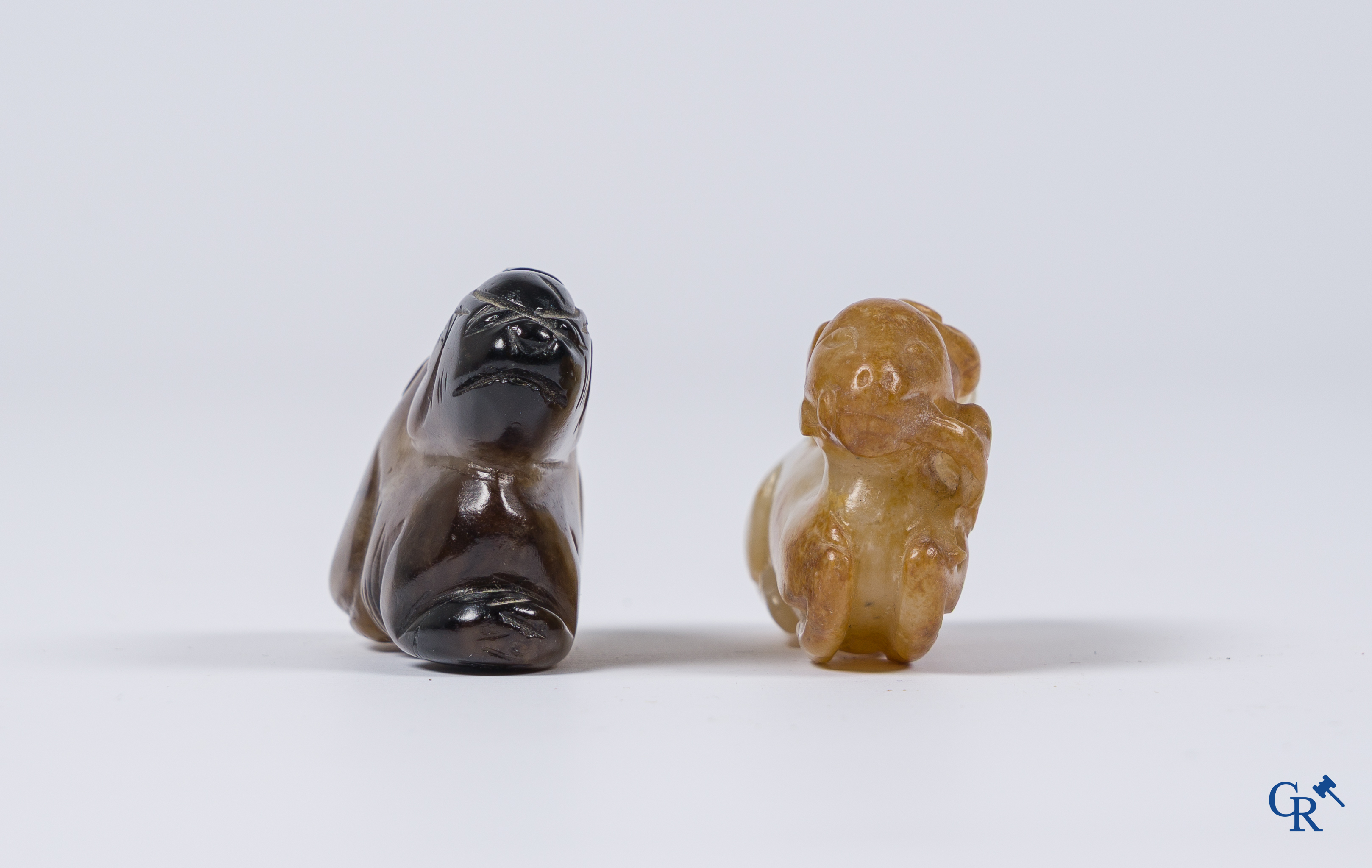 Aziatica. Een bleek celadon en roestbruin kleurige jade hertengroep en een bruinkleurig mythisch beest in jade.