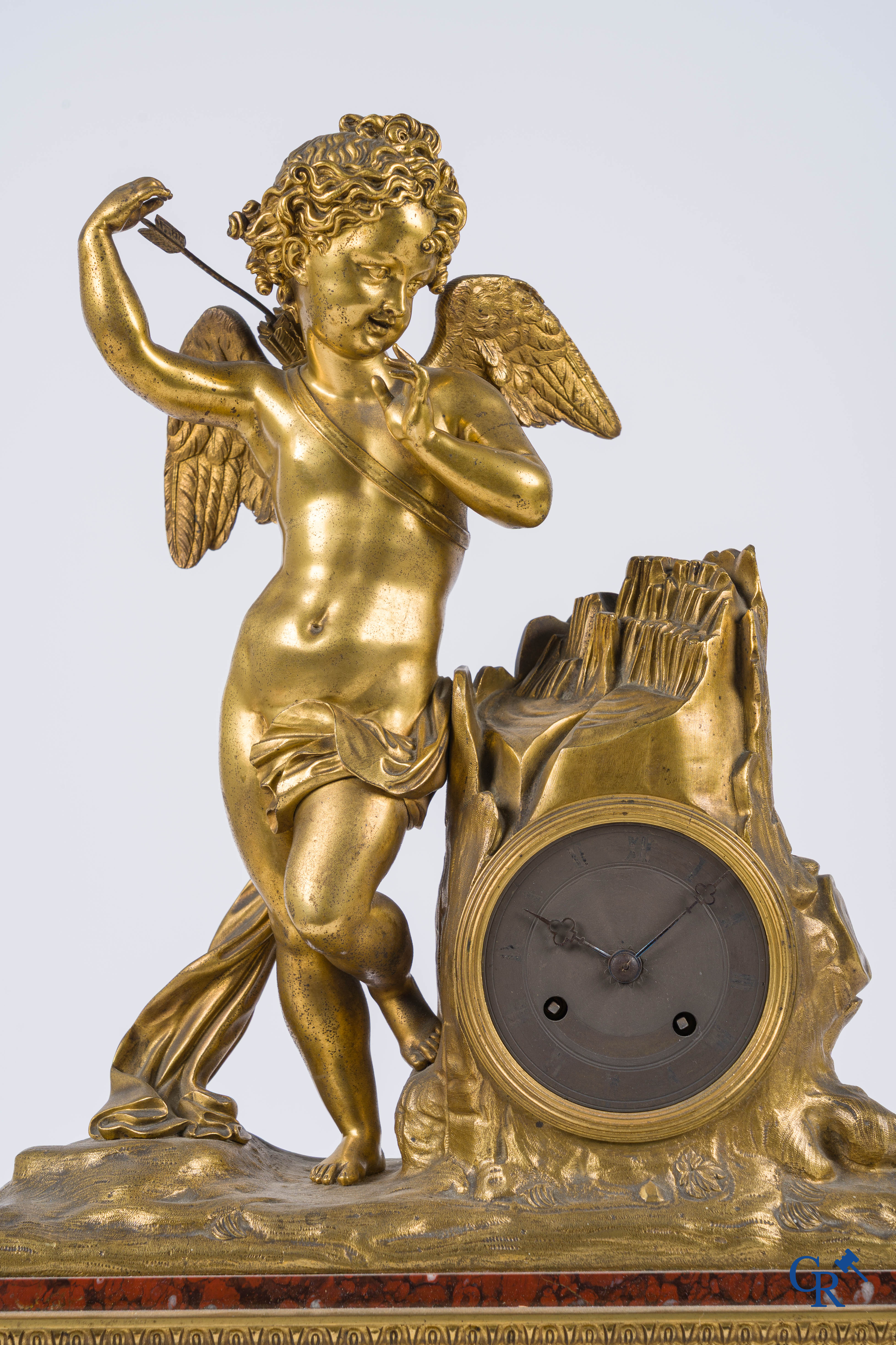Charles X, pendule en bronze au cupidon finement ciselé et doré. Socle en marbre veiné rouge, vers 1840.