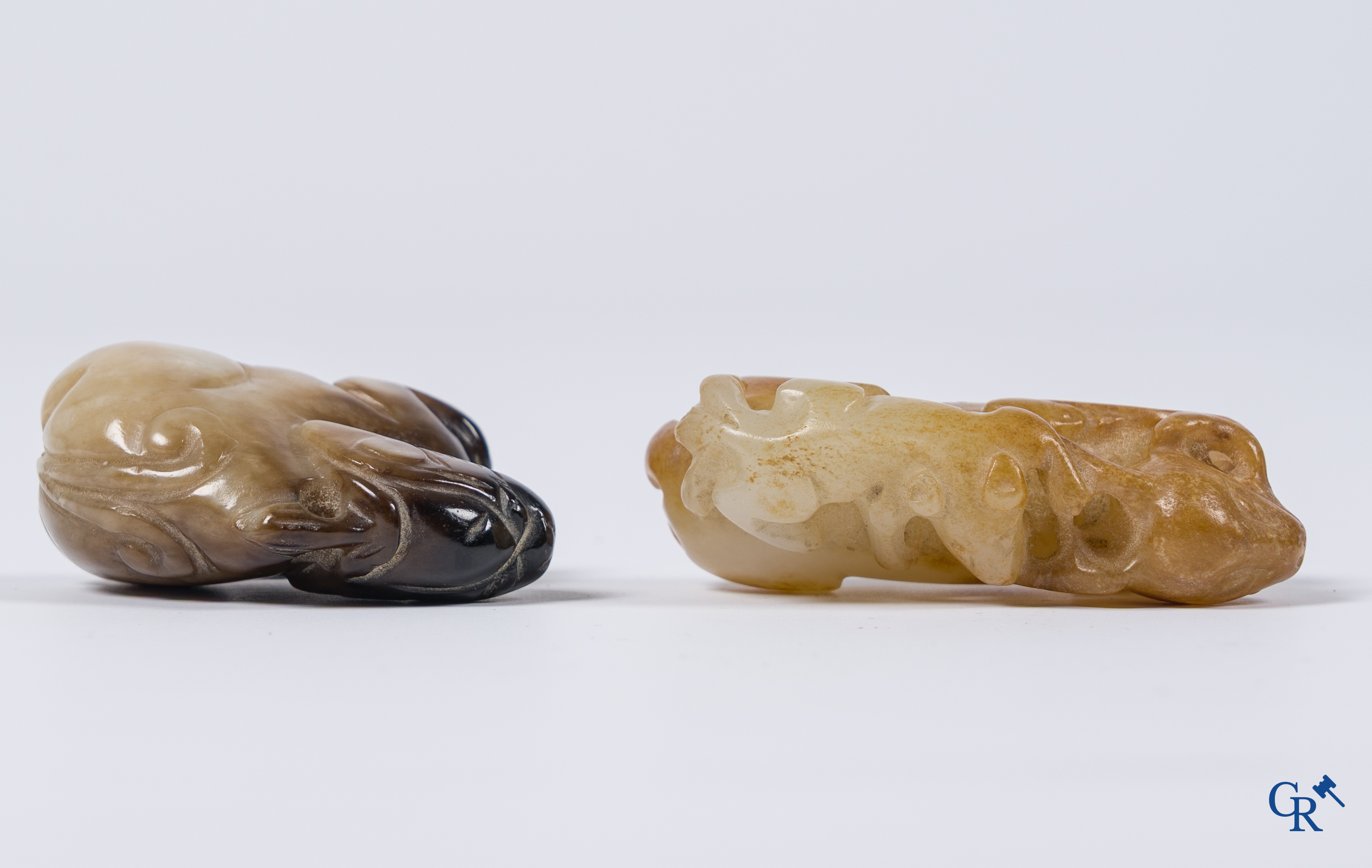 Aziatica. Een bleek celadon en roestbruin kleurige jade hertengroep en een bruinkleurig mythisch beest in jade.