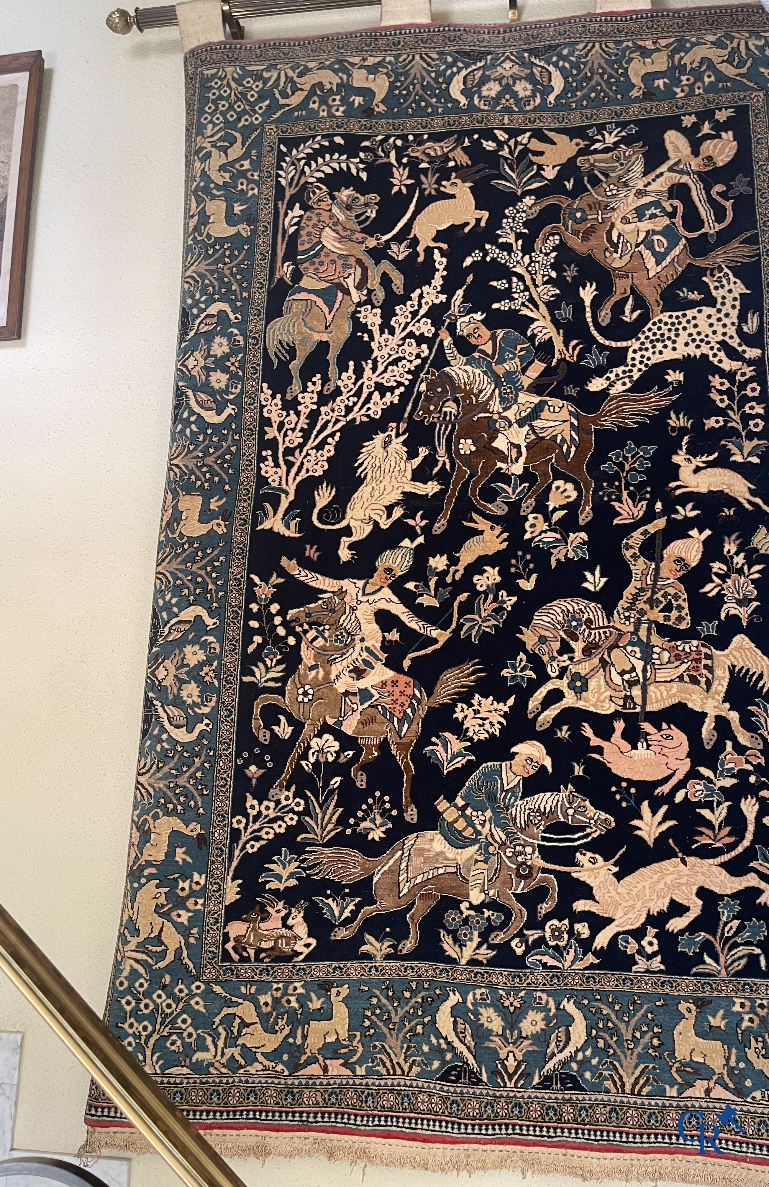 Oosterse tapijten. Ghoum, een fijn geknoopt Perzisch tapijt met ruiters te paard op een donkerblauwe achtergrond.