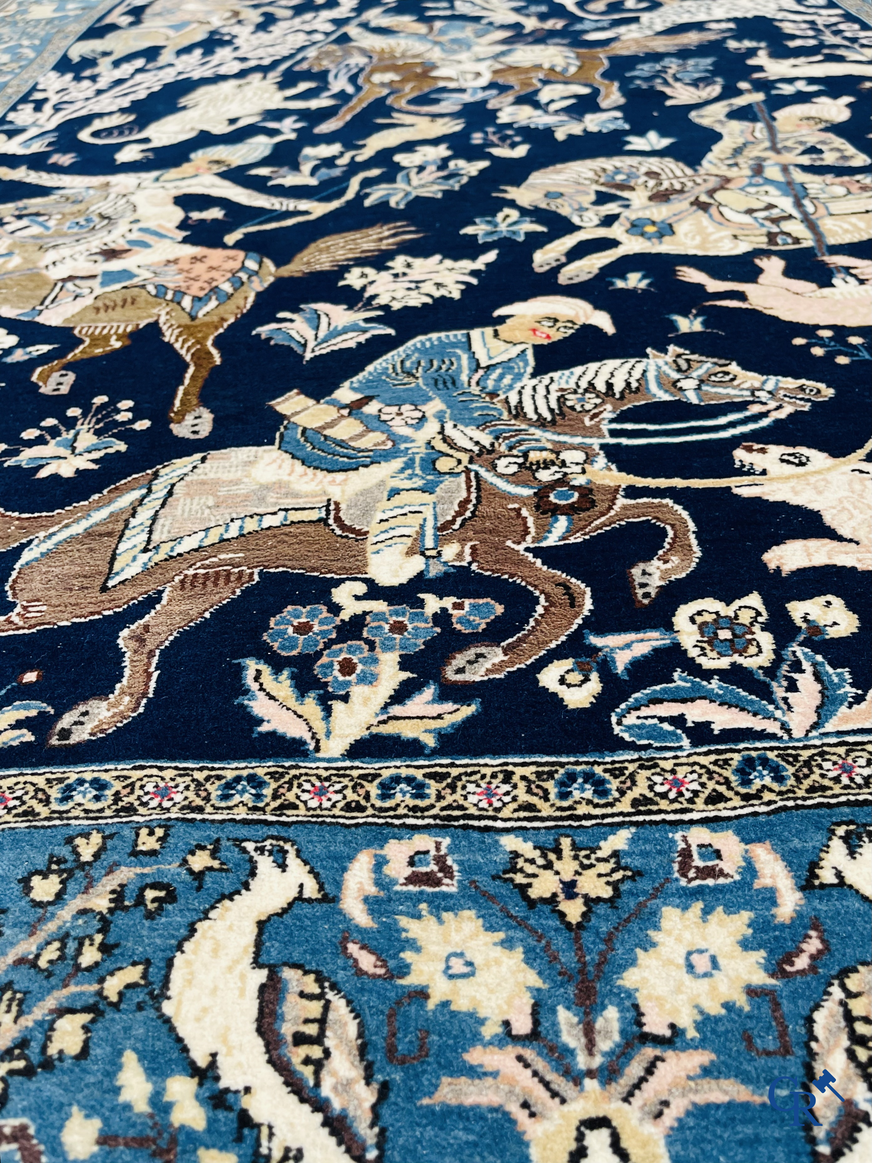 Oosterse tapijten. Ghoum, een fijn geknoopt Perzisch tapijt met ruiters te paard op een donkerblauwe achtergrond.