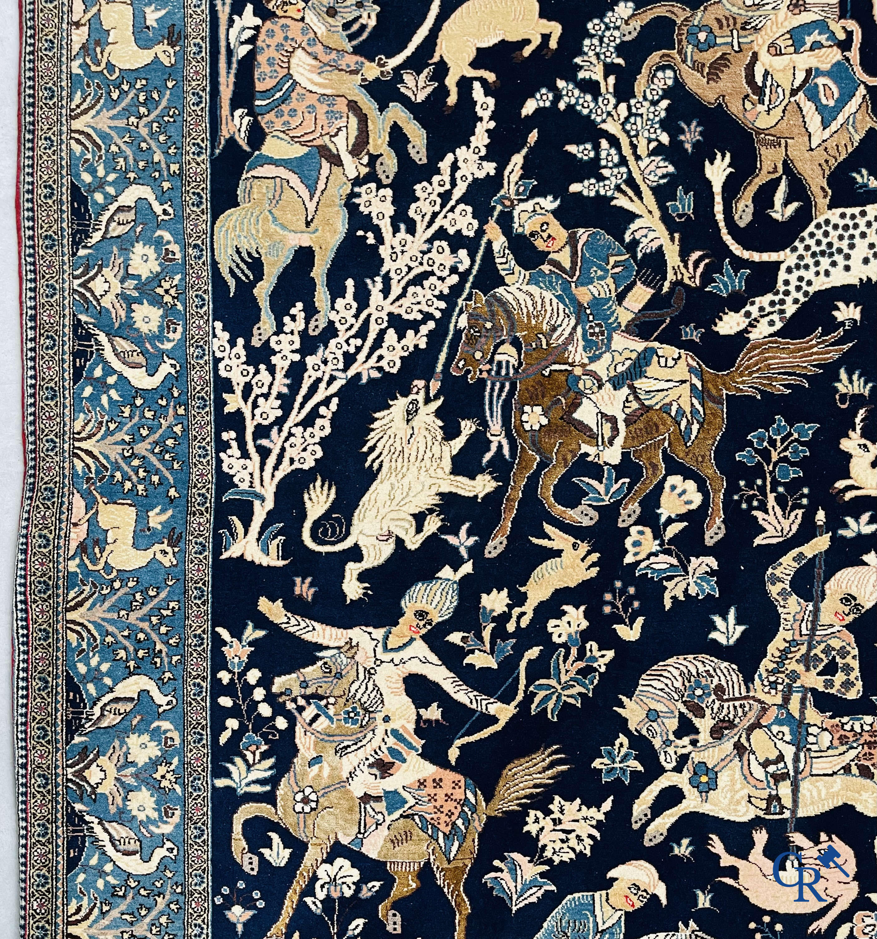 Oosterse tapijten. Ghoum, een fijn geknoopt Perzisch tapijt met ruiters te paard op een donkerblauwe achtergrond.