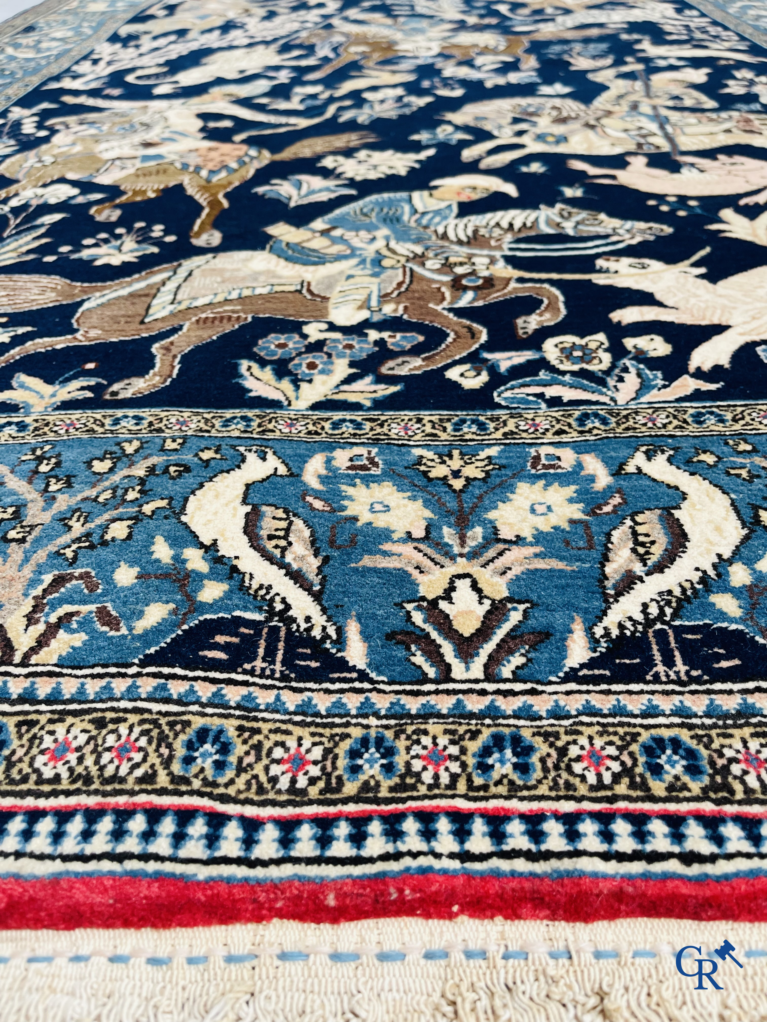 Oosterse tapijten. Ghoum, een fijn geknoopt Perzisch tapijt met ruiters te paard op een donkerblauwe achtergrond.