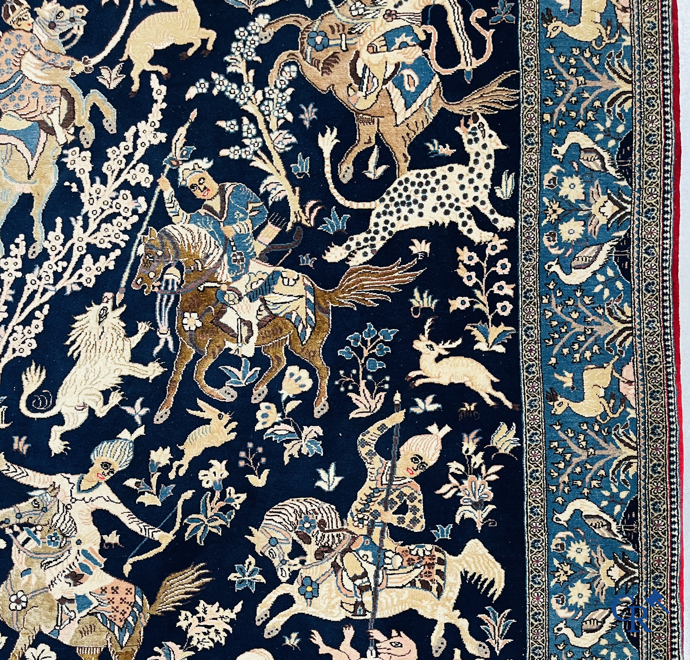 Oosterse tapijten. Ghoum, een fijn geknoopt Perzisch tapijt met ruiters te paard op een donkerblauwe achtergrond.