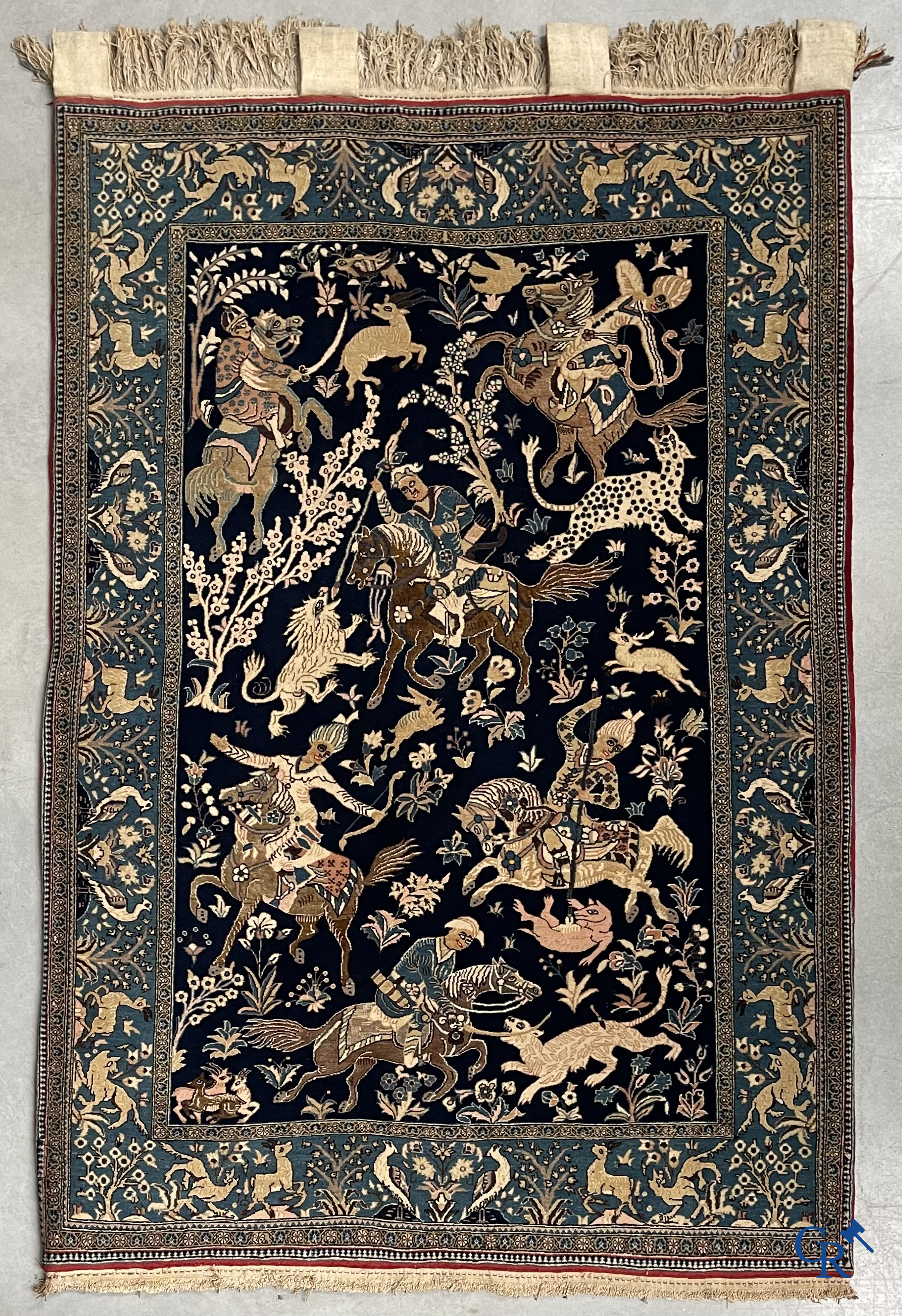 Oosterse tapijten. Ghoum, een fijn geknoopt Perzisch tapijt met ruiters te paard op een donkerblauwe achtergrond.