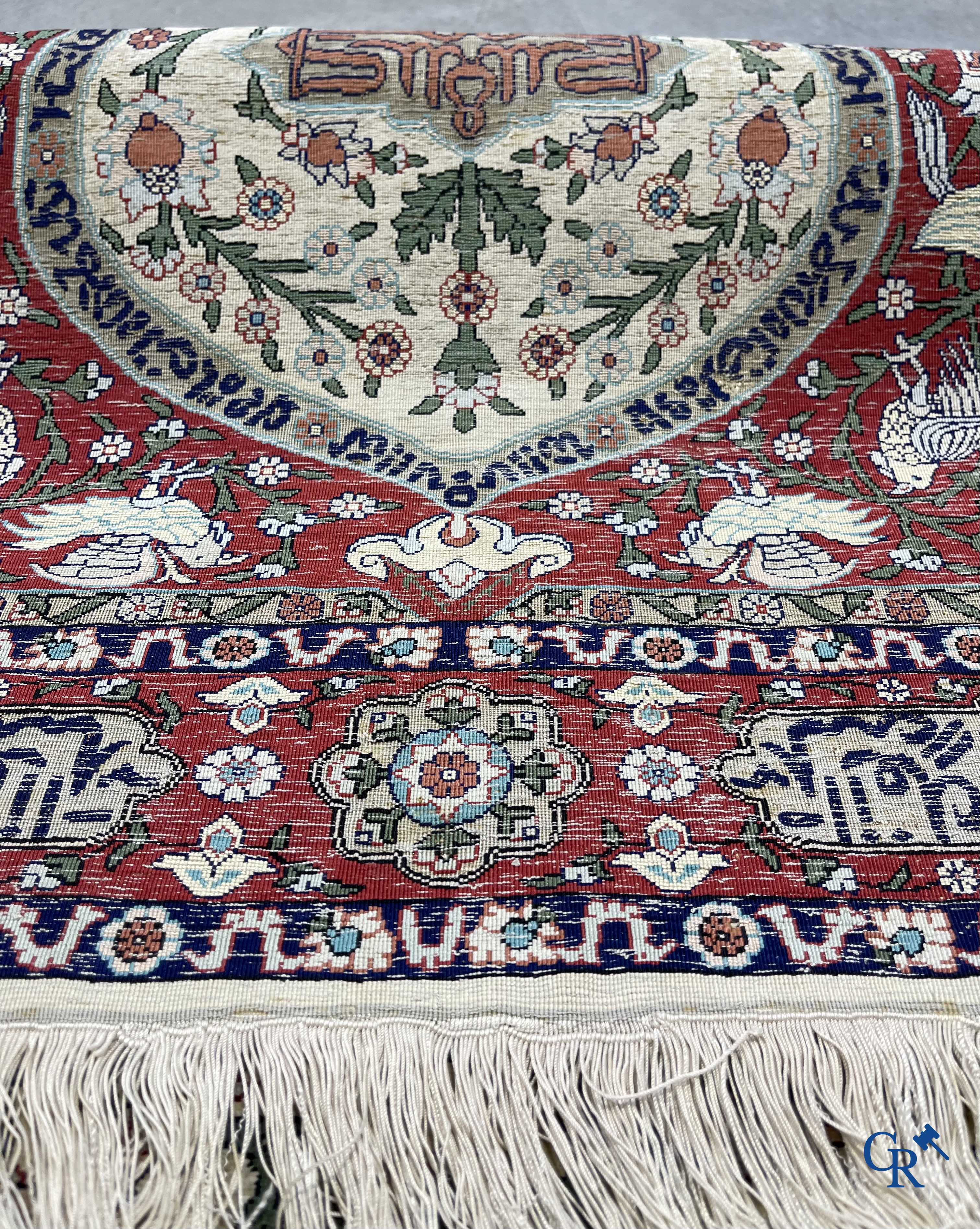 Oosterse tapijten. Een zijden gesigneerd tapijt op donkerrode achtergrond. Inscripties en bewerkt met gouddraad.