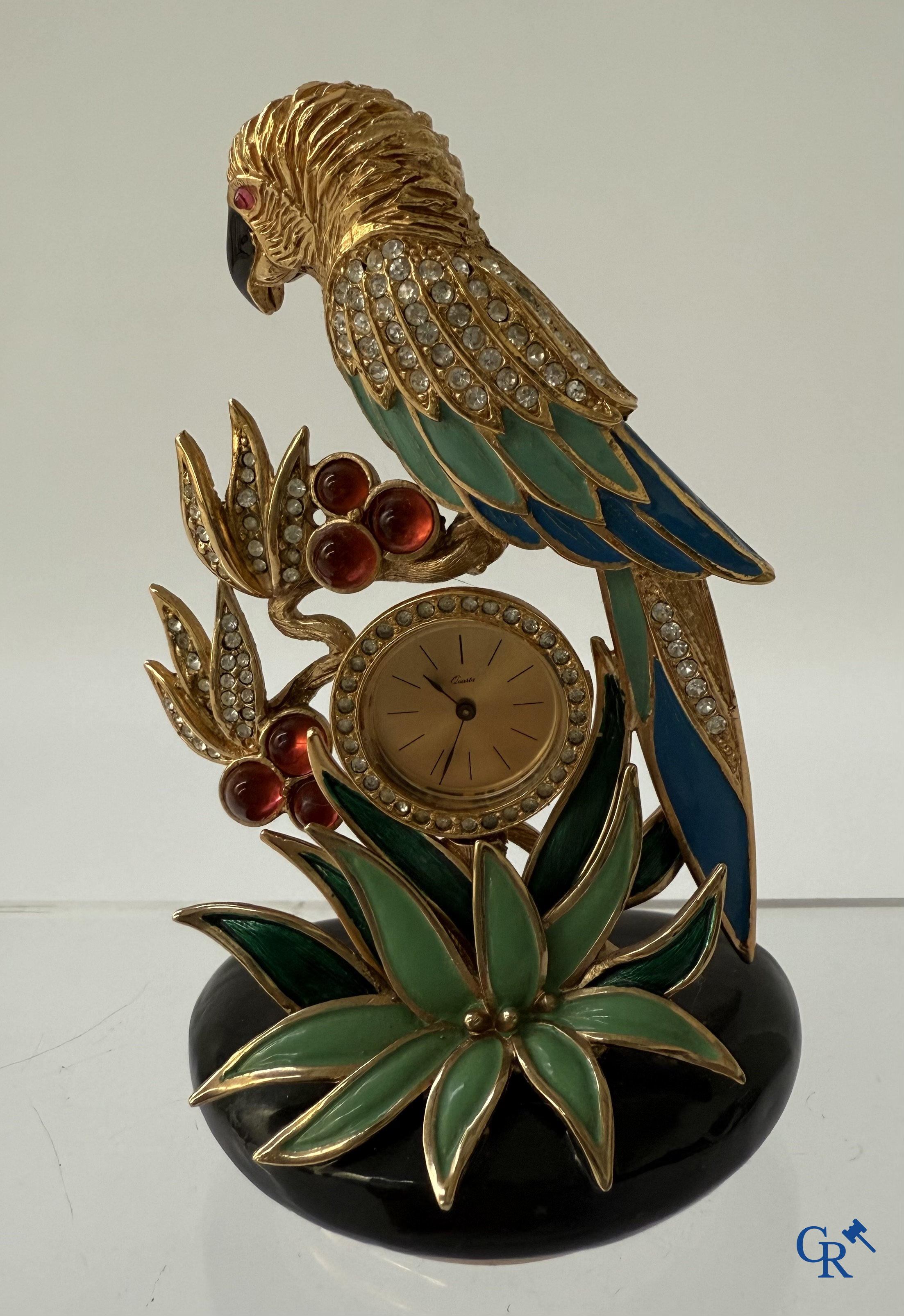 Uurwerken. Een klein klokje met voorstelling van een papegaai. Emaille op verguld metaal ingelegd met gesteente.