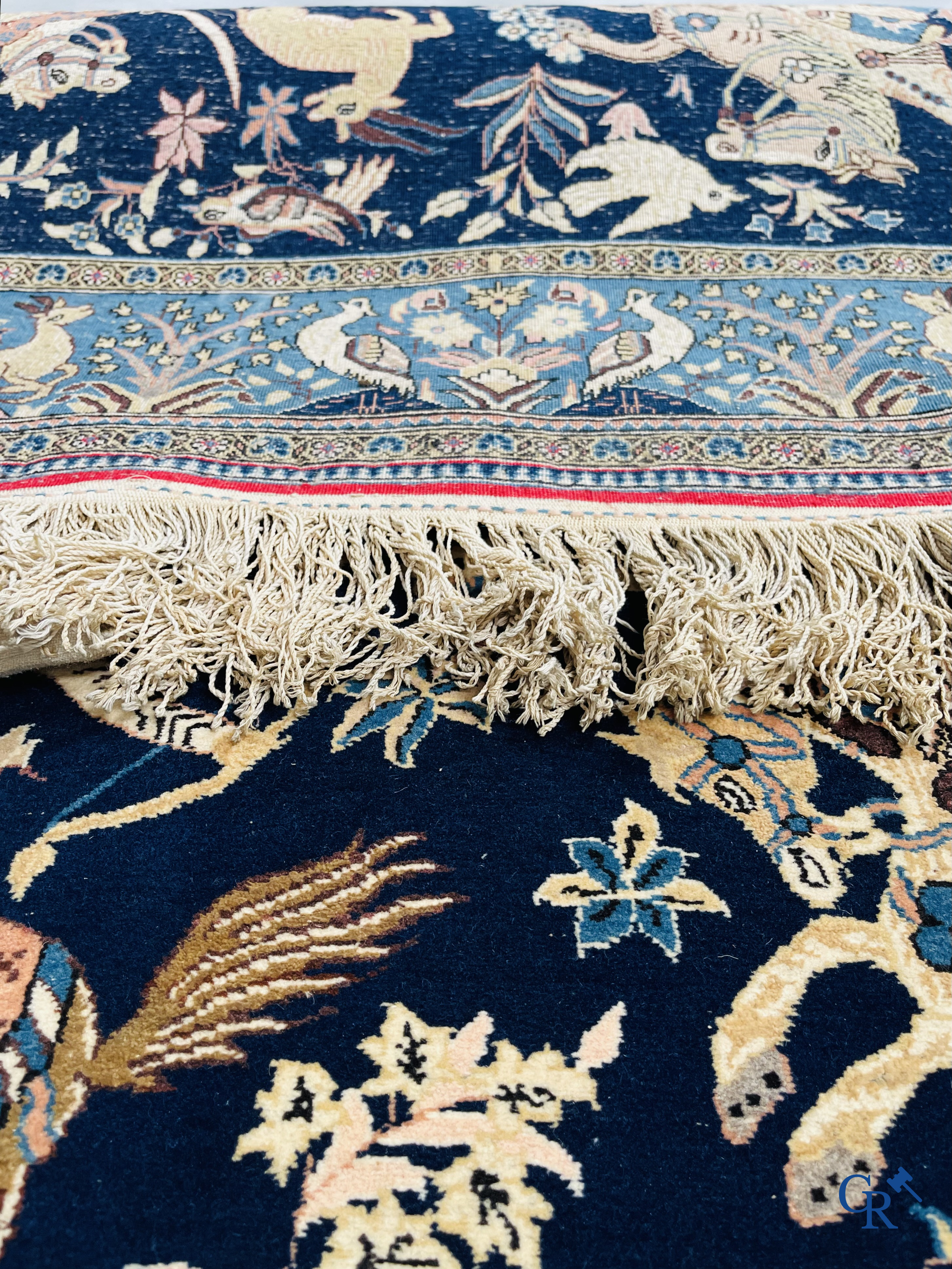 Oosterse tapijten. Ghoum, een fijn geknoopt Perzisch tapijt met ruiters te paard op een donkerblauwe achtergrond.