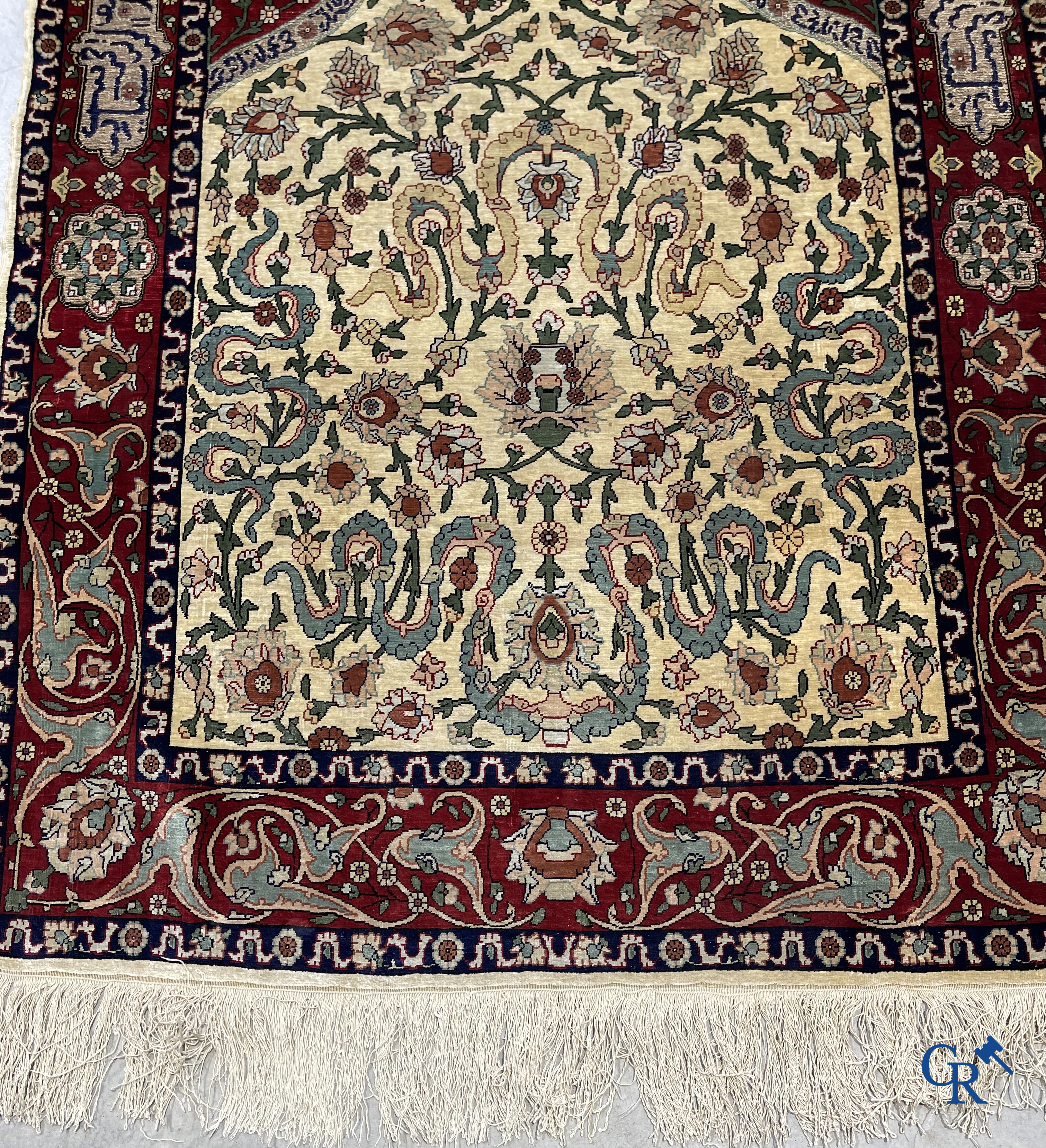 Oosterse tapijten. Een zijden gesigneerd tapijt op donkerrode achtergrond. Inscripties en bewerkt met gouddraad.