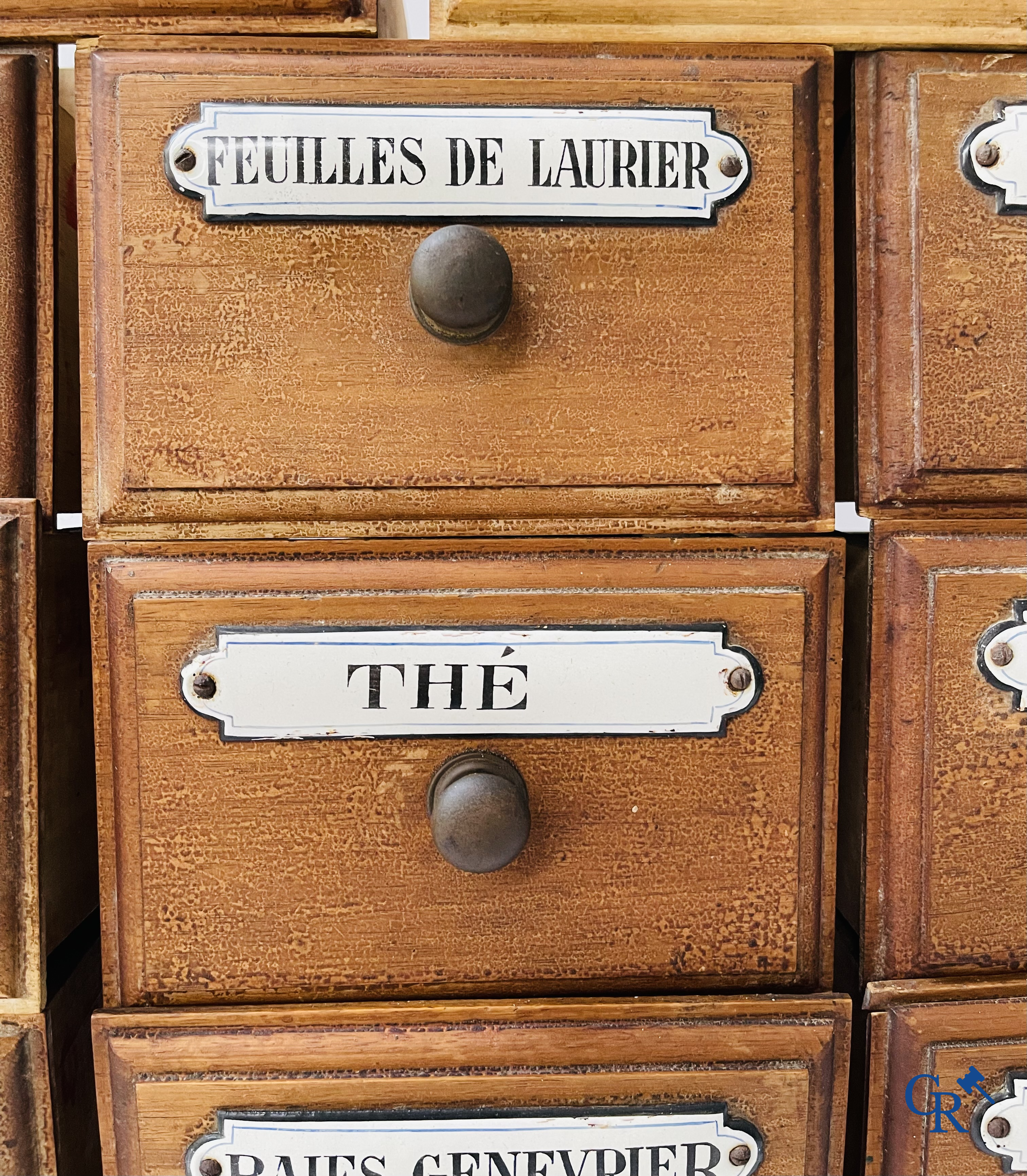 14 laden met emaille bordjes voor kruiden, specerijen en andere afkomstig van een winkelmeubel. Circa 1920.
