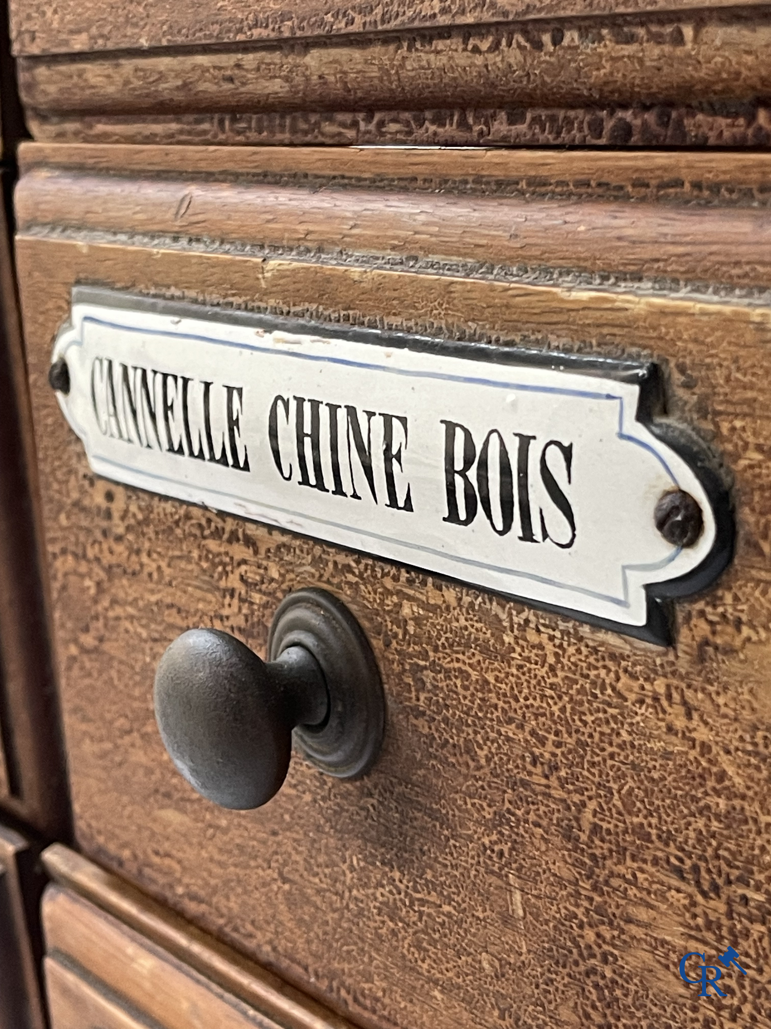 14 laden met emaille bordjes voor kruiden, specerijen en andere afkomstig van een winkelmeubel. Circa 1920.