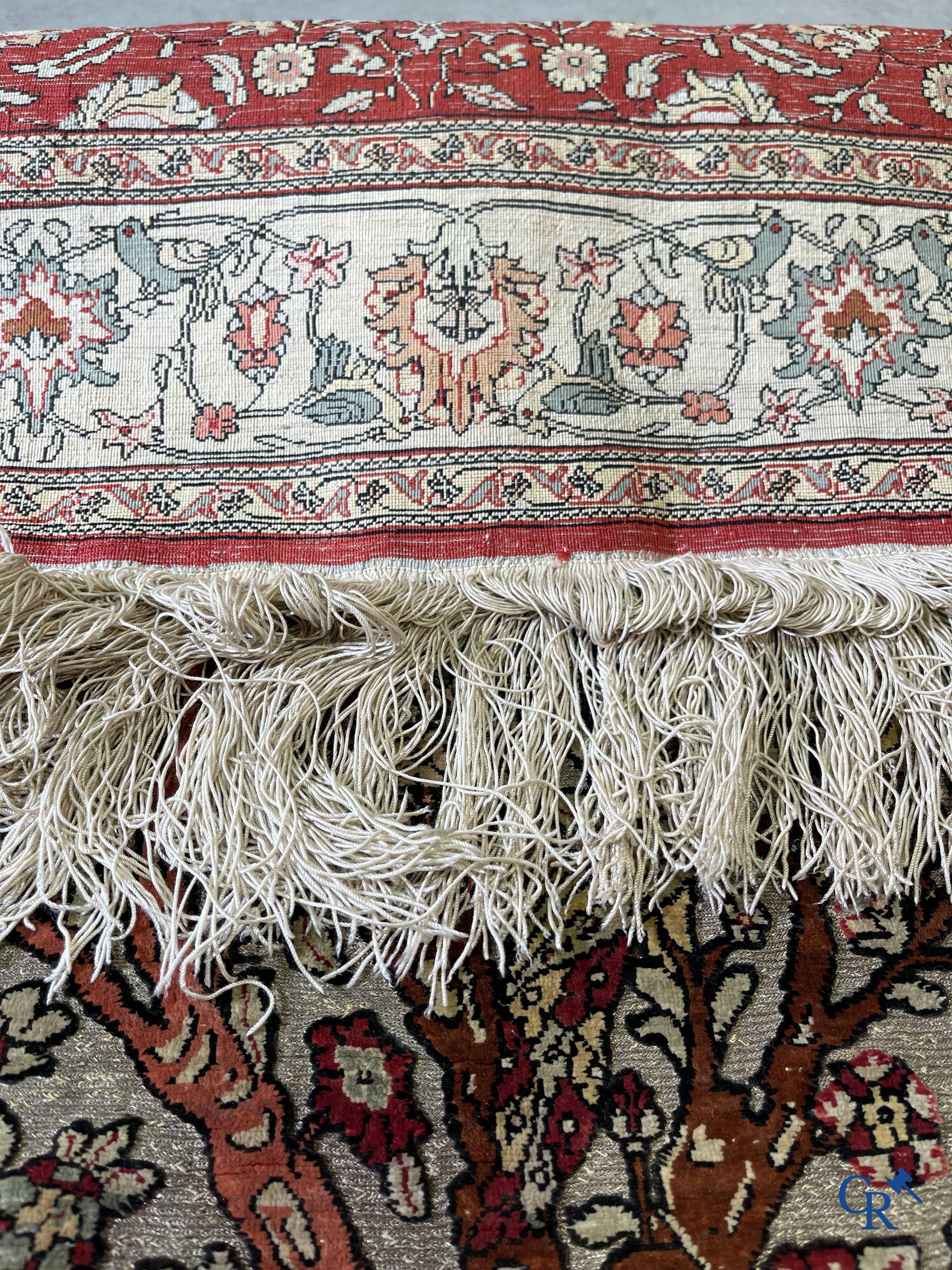 Oriental carpets, a hand-knotted carpet in silk with forest animals in a floral decor on a background in gold thread.
