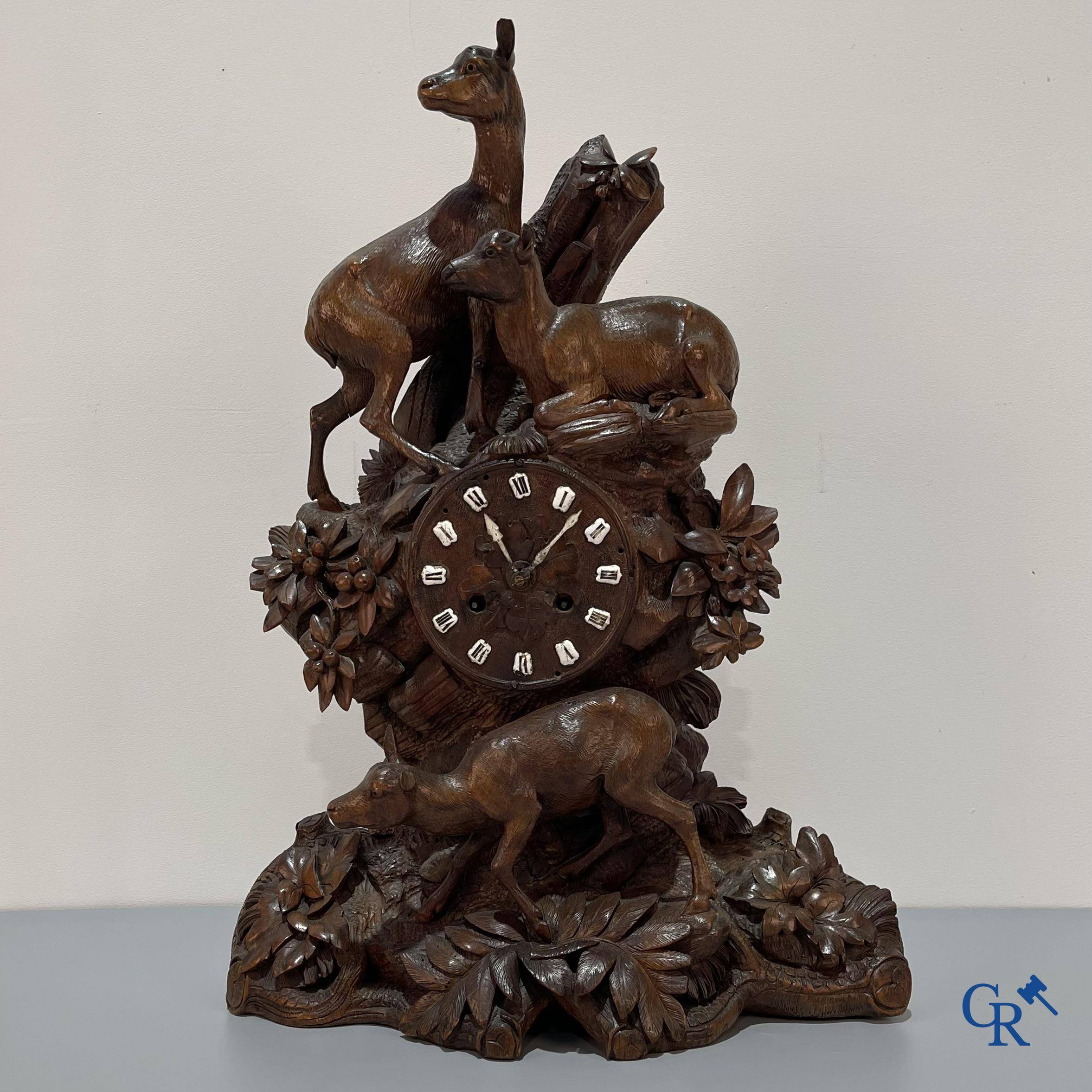 A wood sculpted Black Forest clock with deer in their flora. Germany, late 19th century.