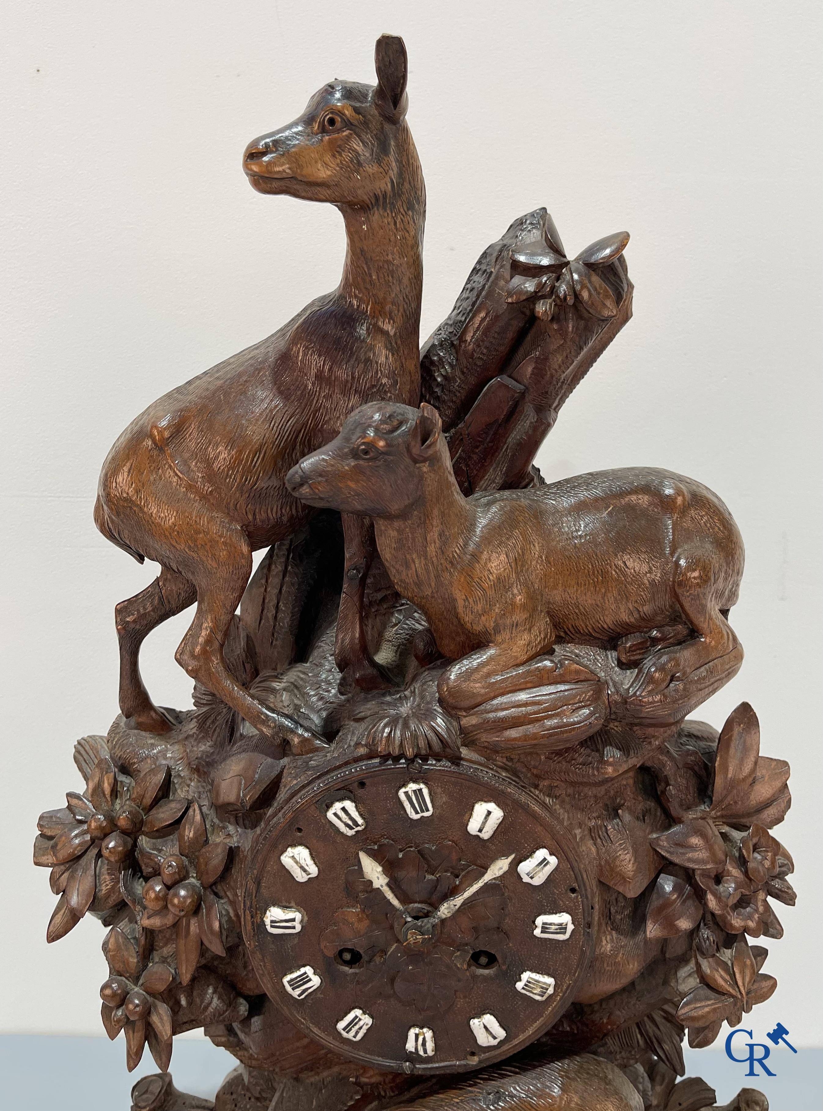 A wood sculpted Black Forest clock with deer in their flora. Germany, late 19th century.