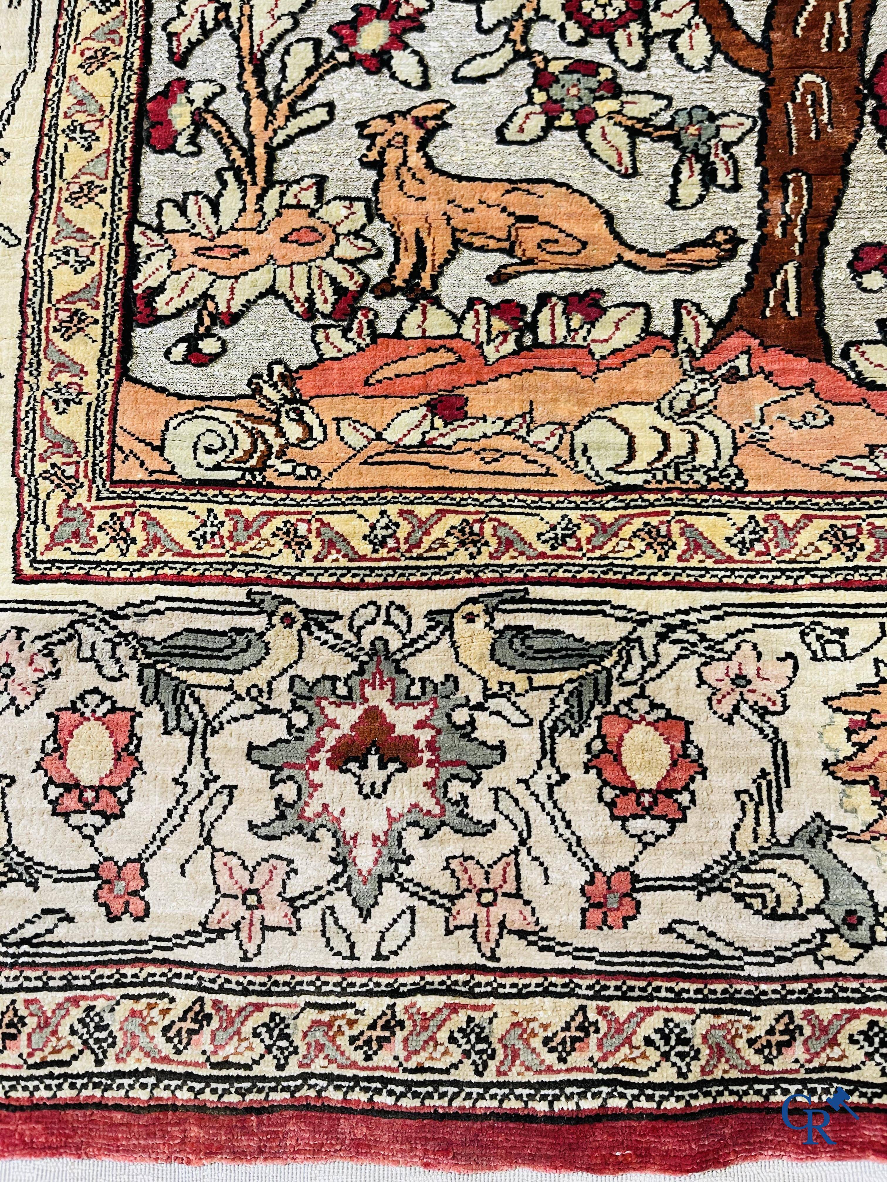 Oriental carpets, a hand-knotted carpet in silk with forest animals in a floral decor on a background in gold thread.