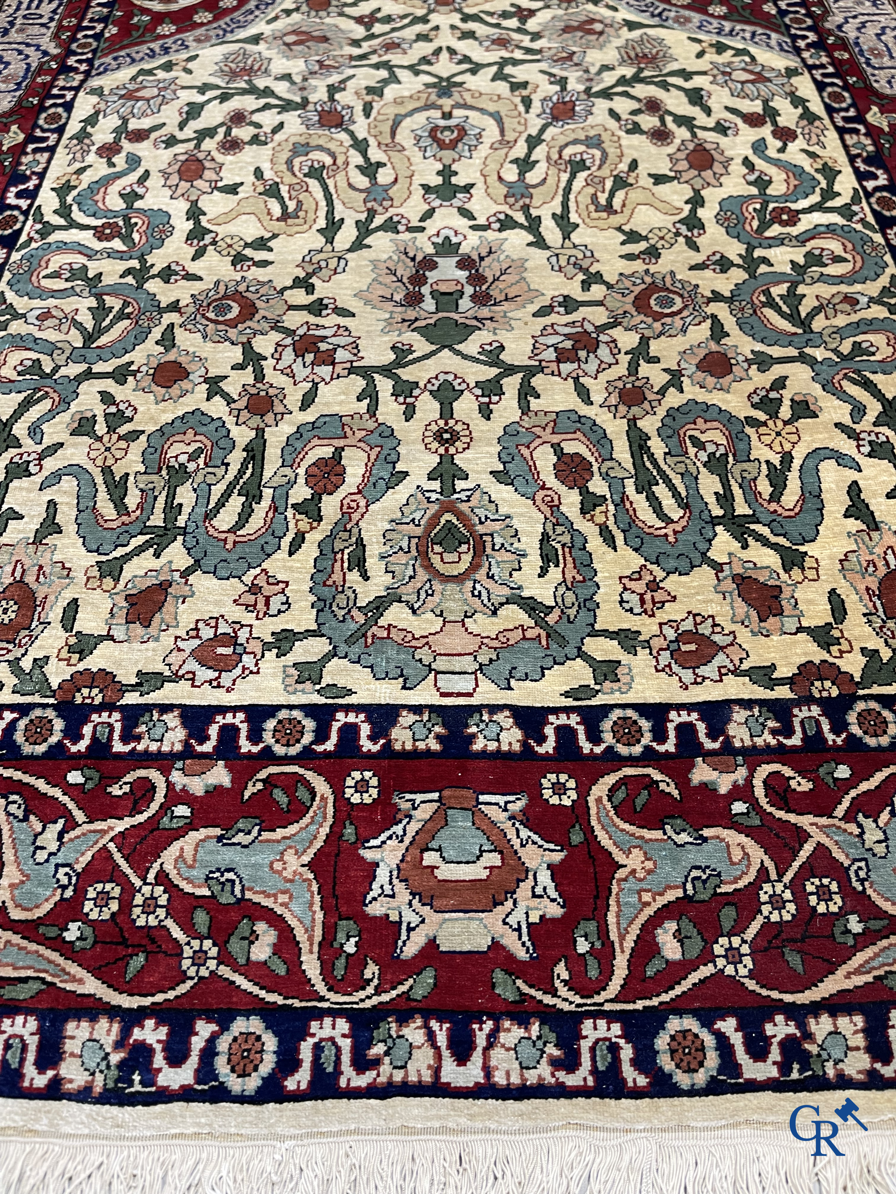 Oosterse tapijten. Een zijden gesigneerd tapijt op donkerrode achtergrond. Inscripties en bewerkt met gouddraad.