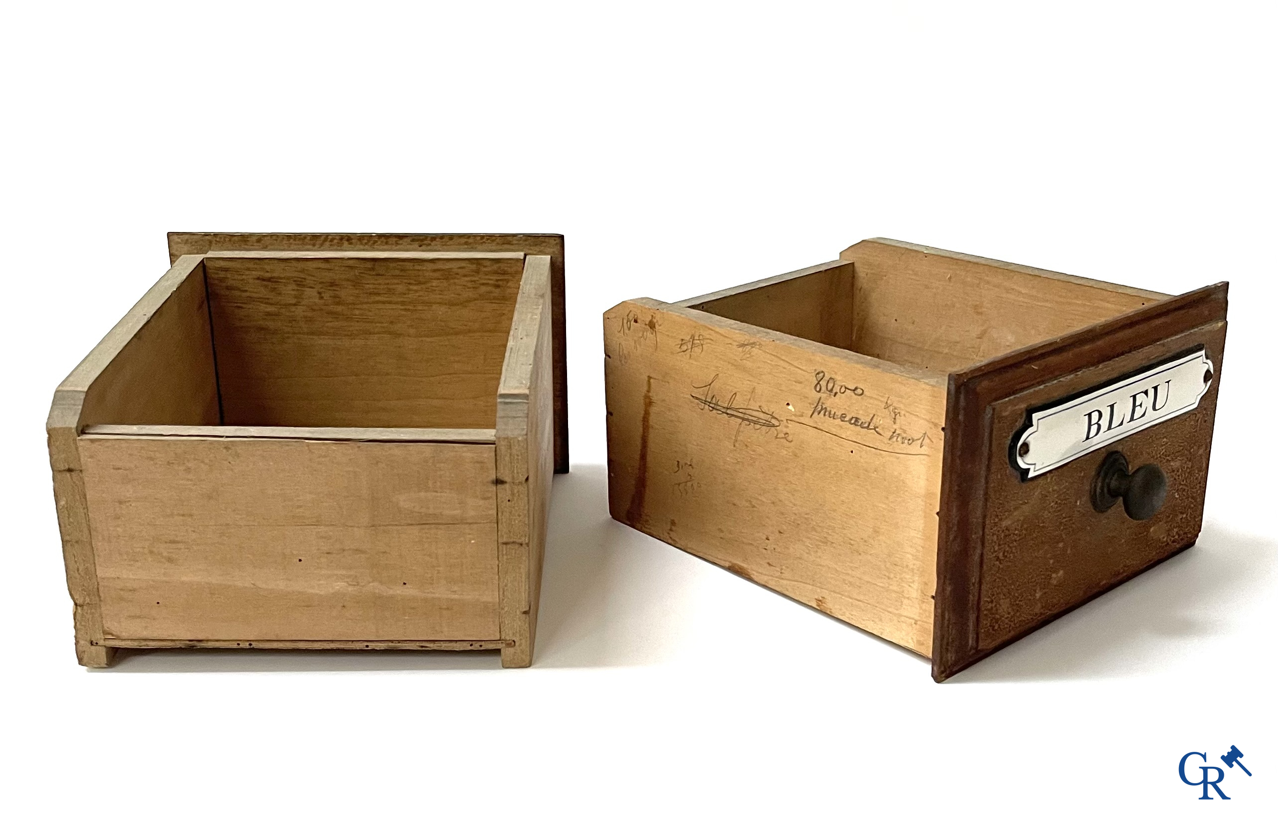 14 laden met emaille bordjes voor kruiden, specerijen en andere afkomstig van een winkelmeubel. Circa 1920.