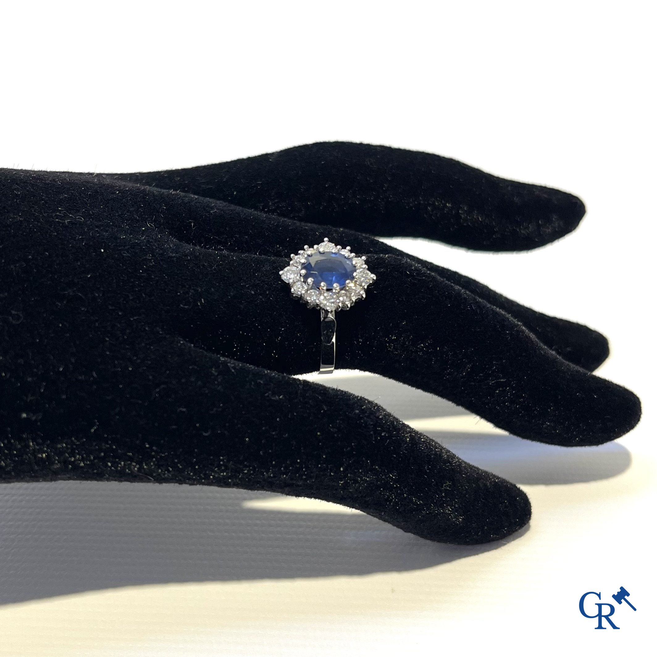 Jewellery. Ring in white gold 750°/00 set with a central blue sapphire surrounded by 12 small diamonds.