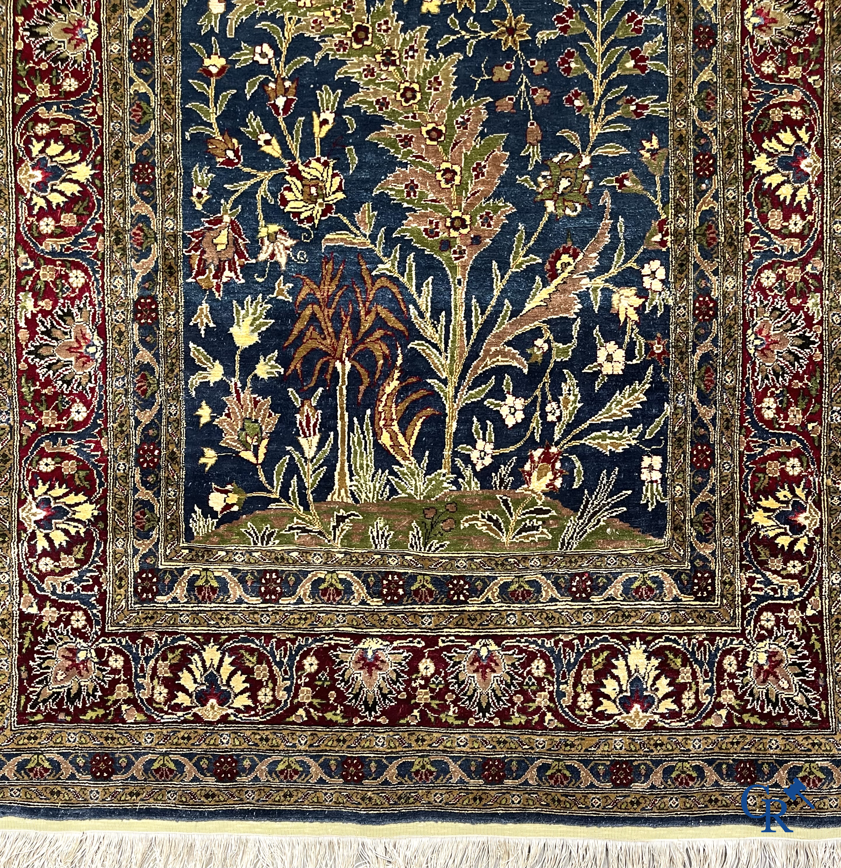 Oosterse tapijten. Een uiterst fijn geknoopt zijden tapijt met floraal decor op donker blauwe achtergrond en gouddraad.